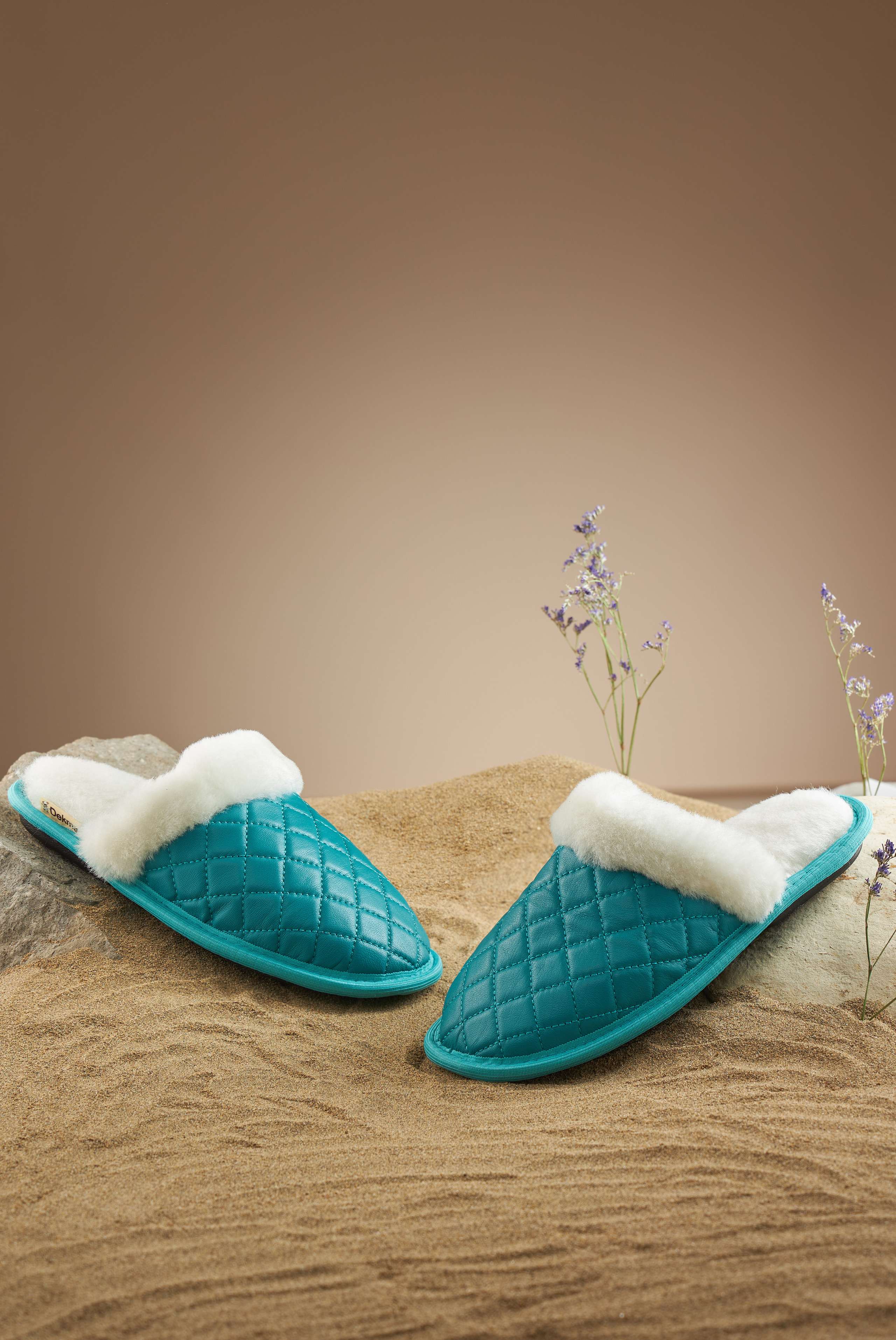 Зеленые тапочки на песке, коричневый фон