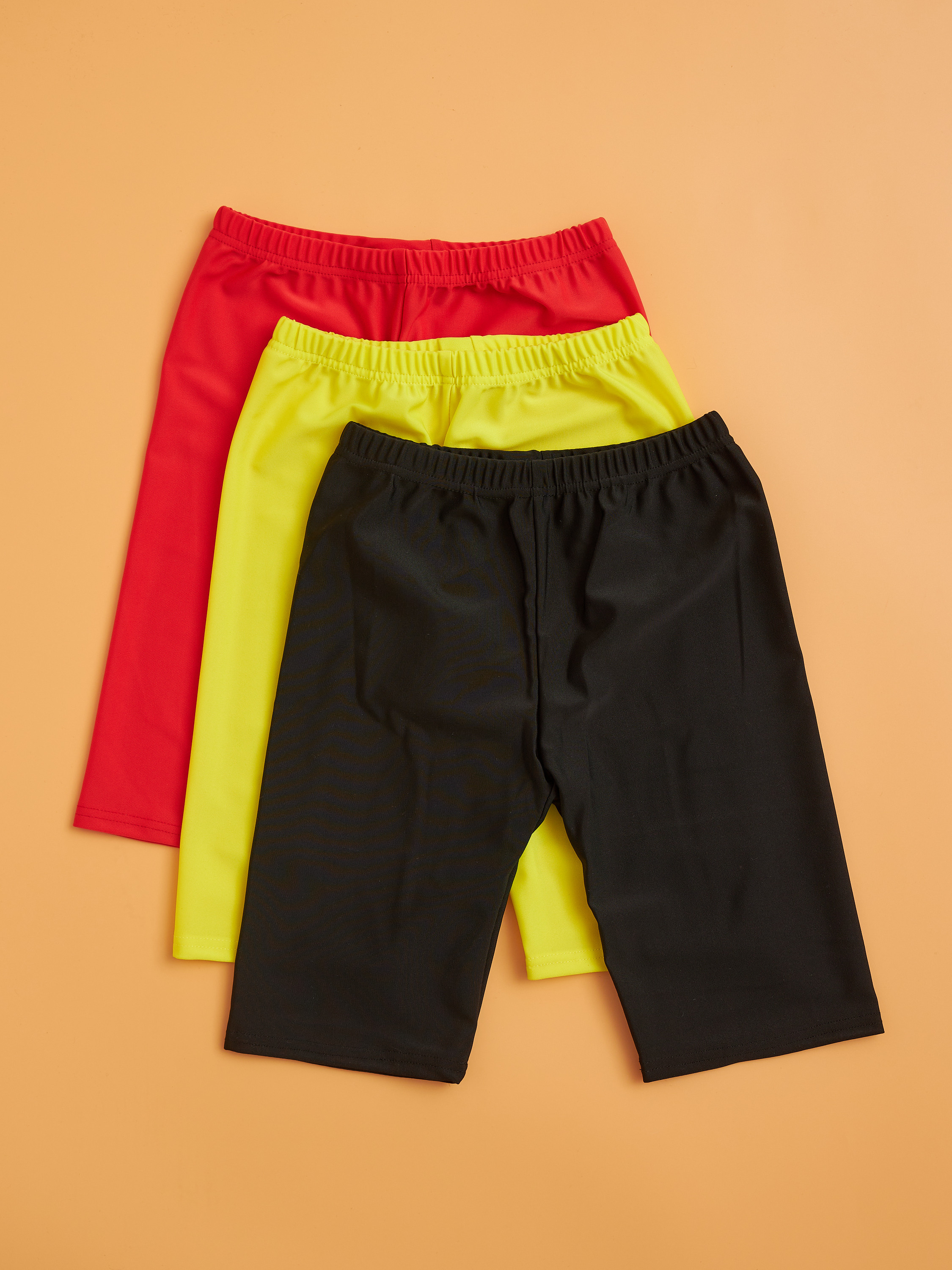 Шорты красные, желтые, черные на бежевом фоне.