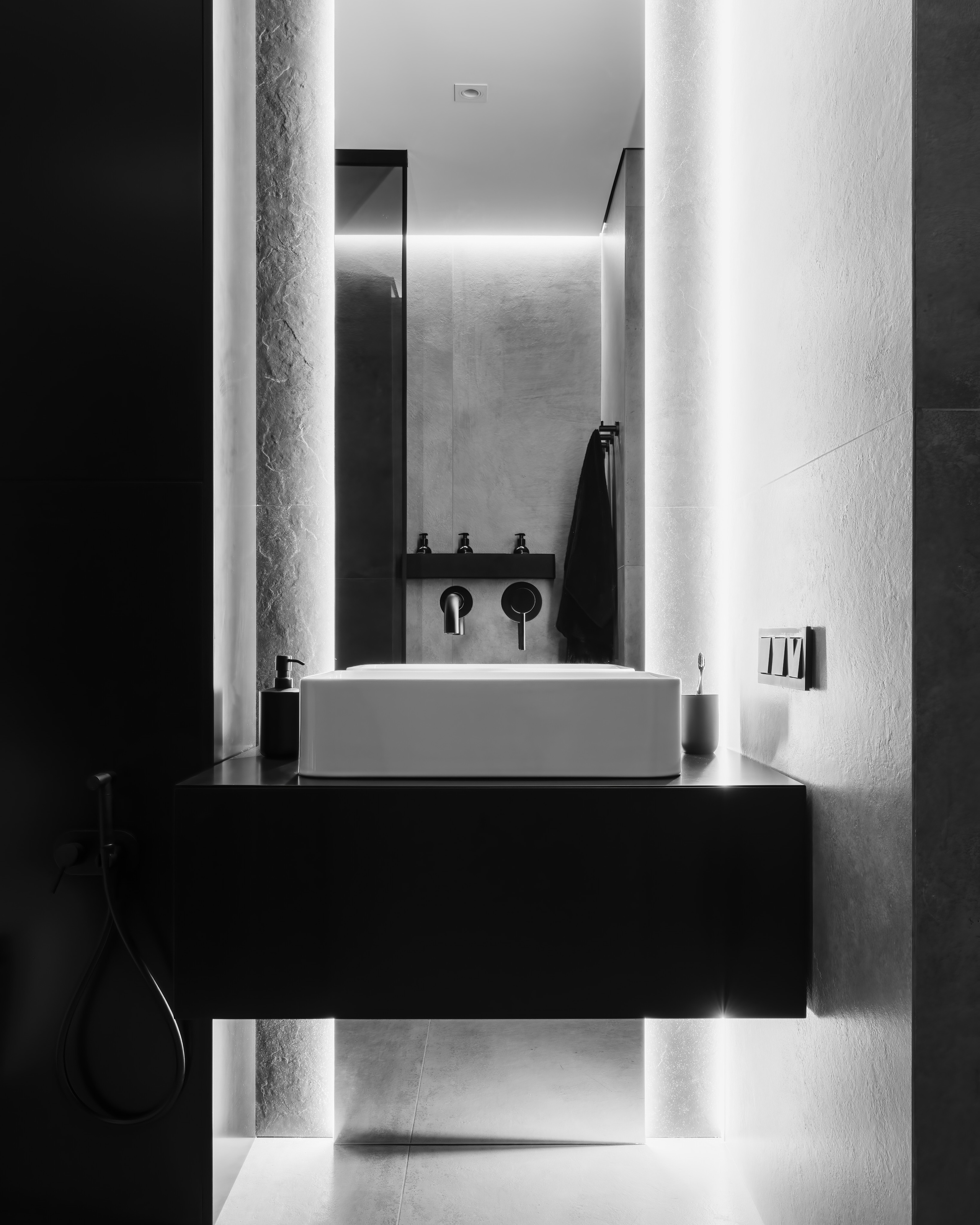 Современный санузел в стиле минимализм с подвесной тумбой и прямоугольной раковиной, встроенной подсветкой стен и матовыми чёрными смесителями, интерьер от дизайнера Анатолия Котова, фотограф Сергей Денисенко.