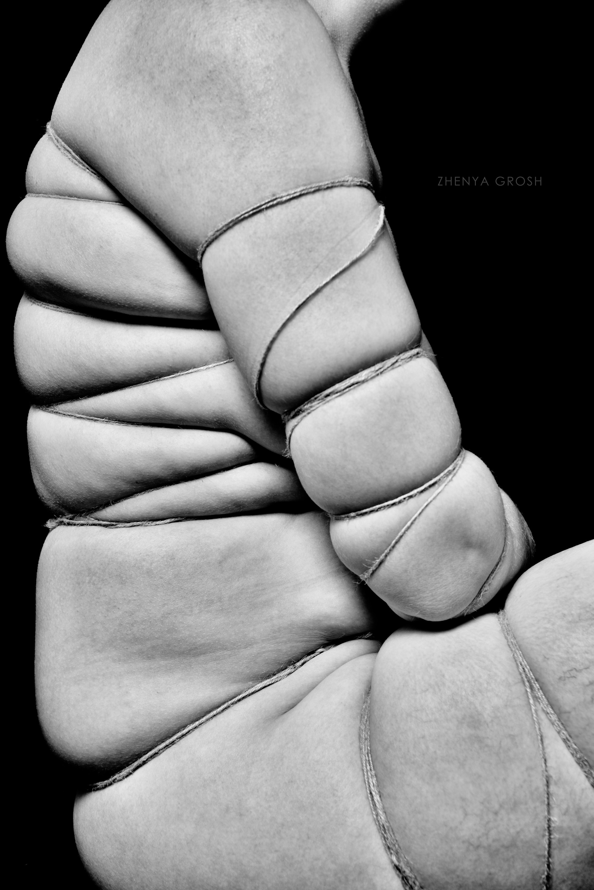 Тело обвязано веревкой сидя на черном фоне 