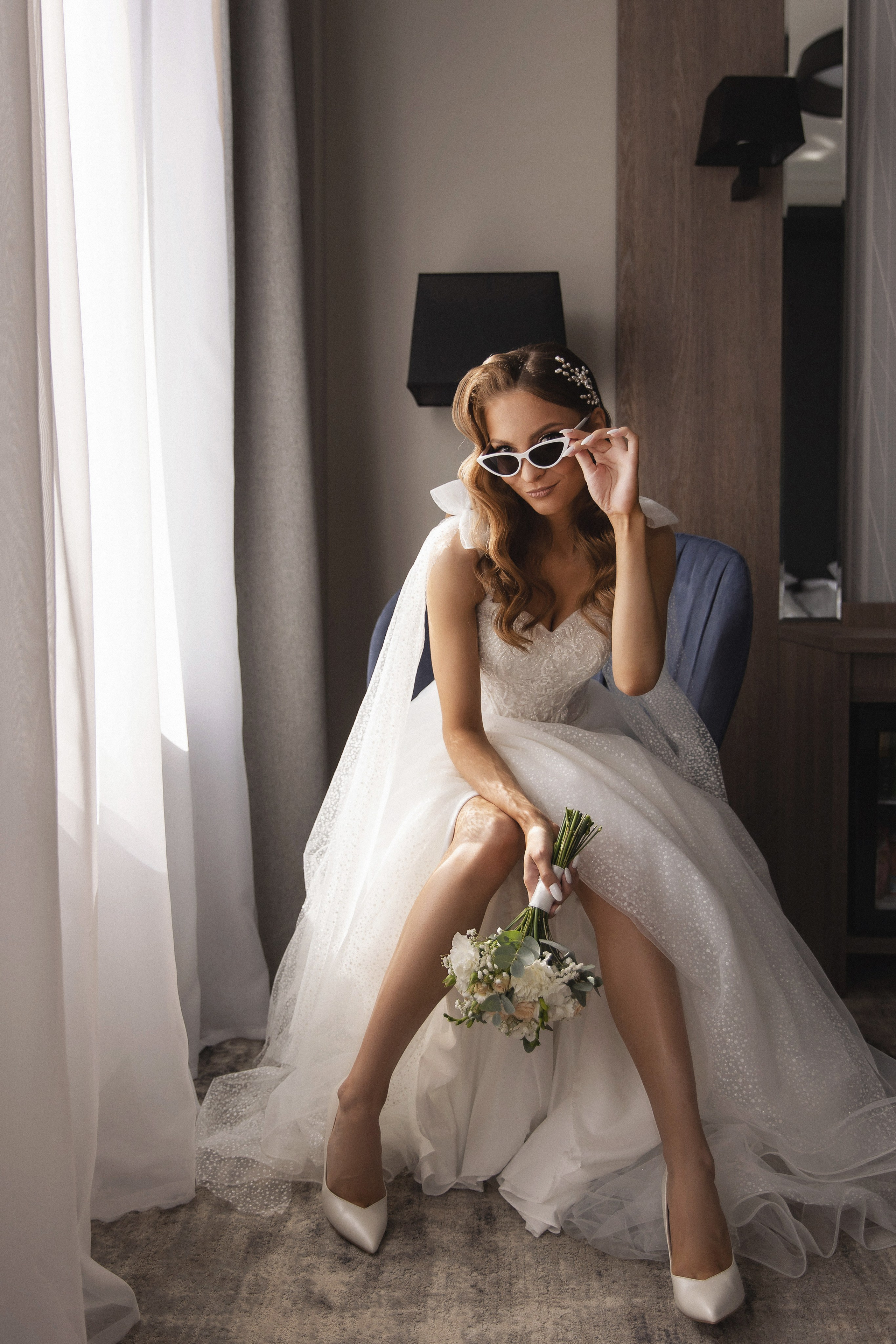 Красавица невеста сидит на стуле и держит букет