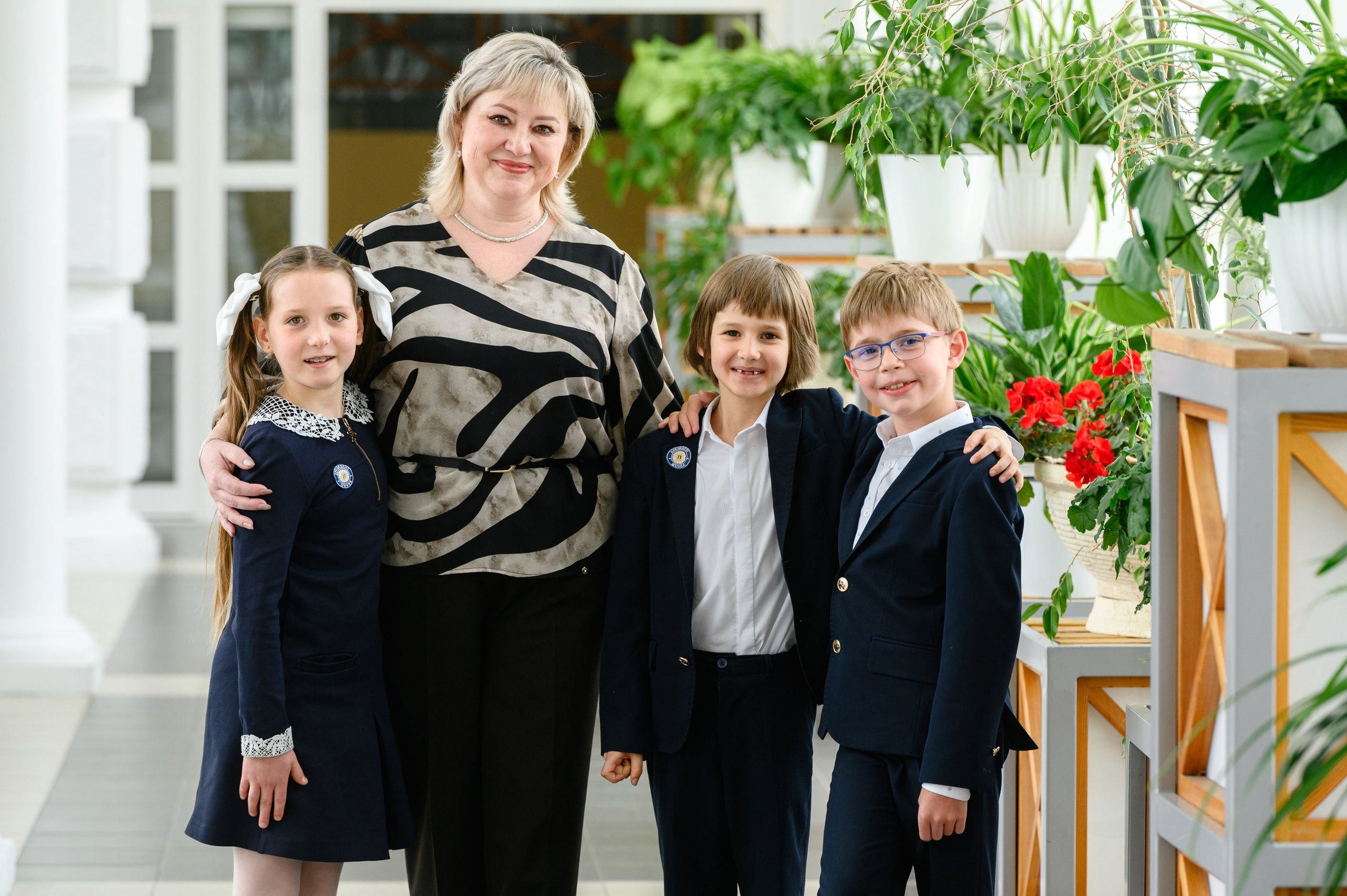 Учительница стоит с тремя учениками в школьном коридоре