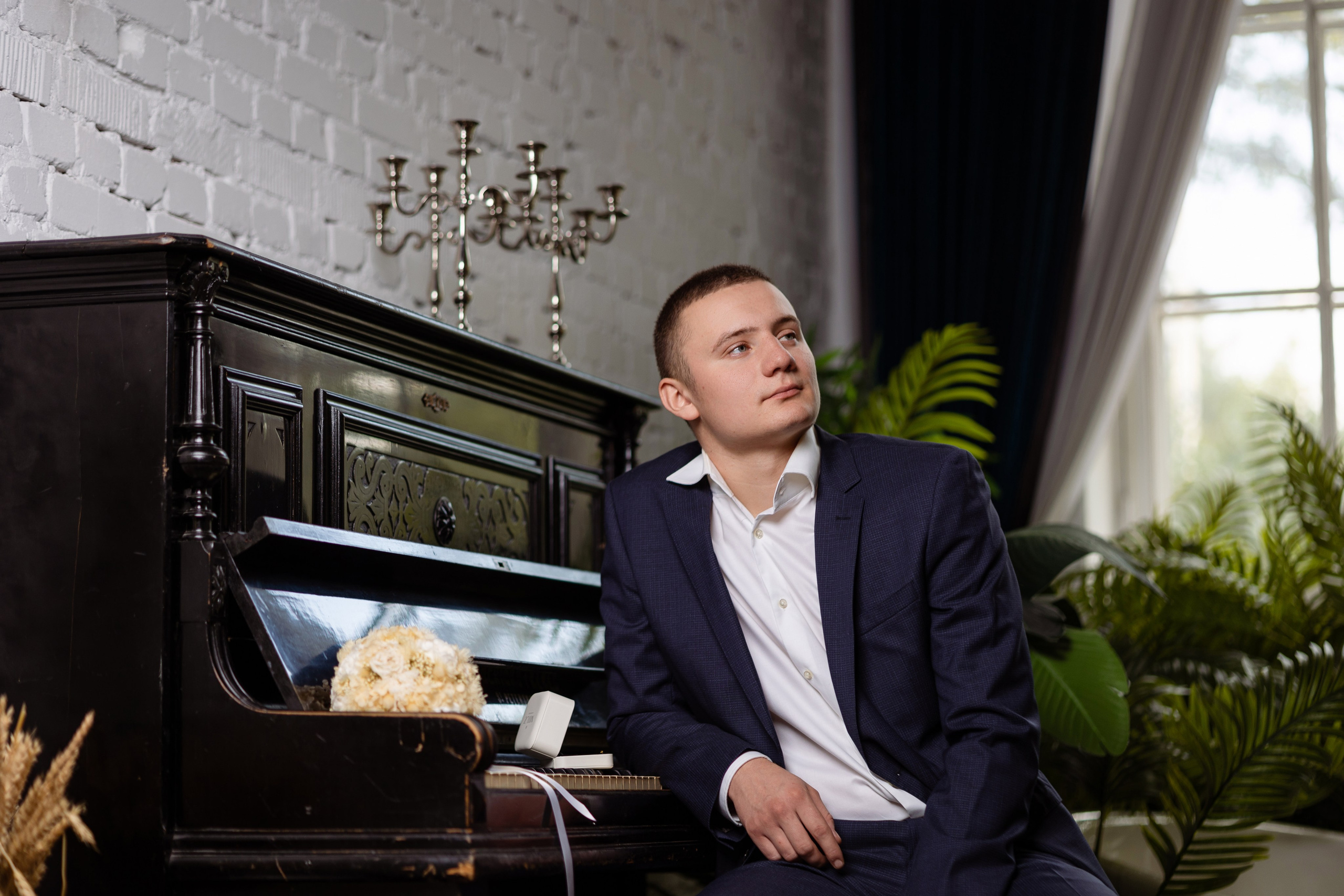Жених сидит возле фортепиано, на котором лежит букет невесты.