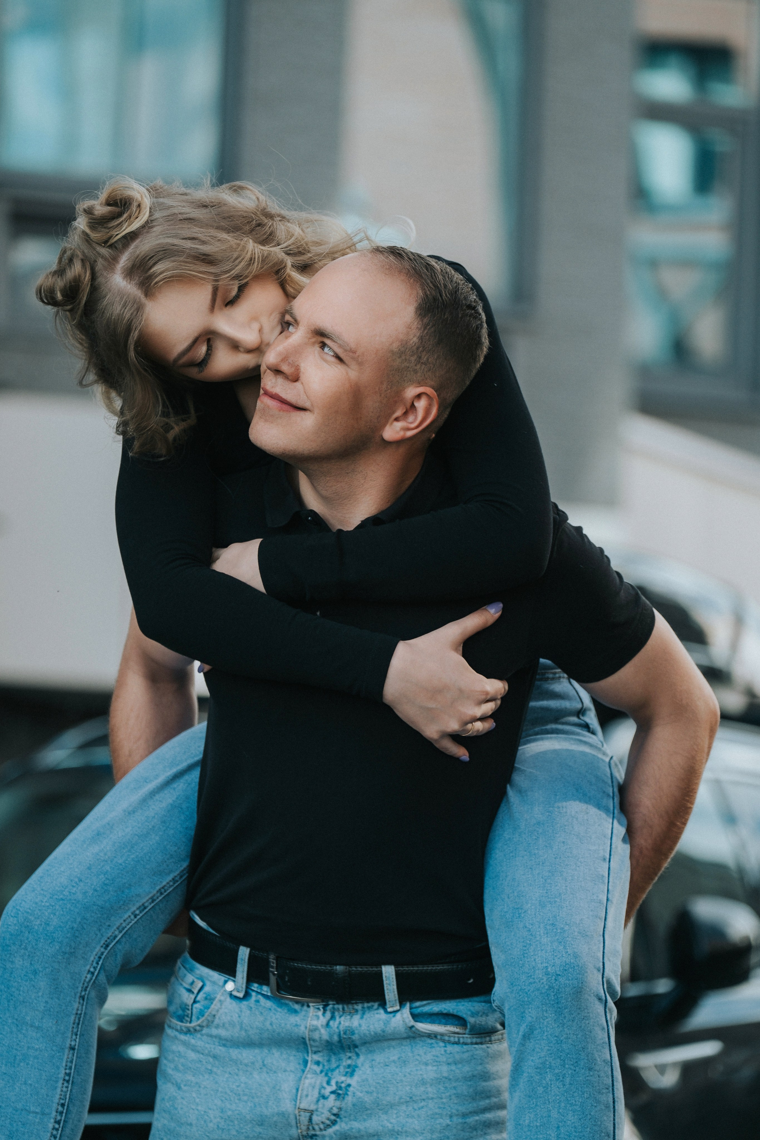 Молодая пара мужчина и девушка дурачатся в городских локациях в черных футболках и синих джинсах, лав стори для влюбленной пары на кануне свадьбы