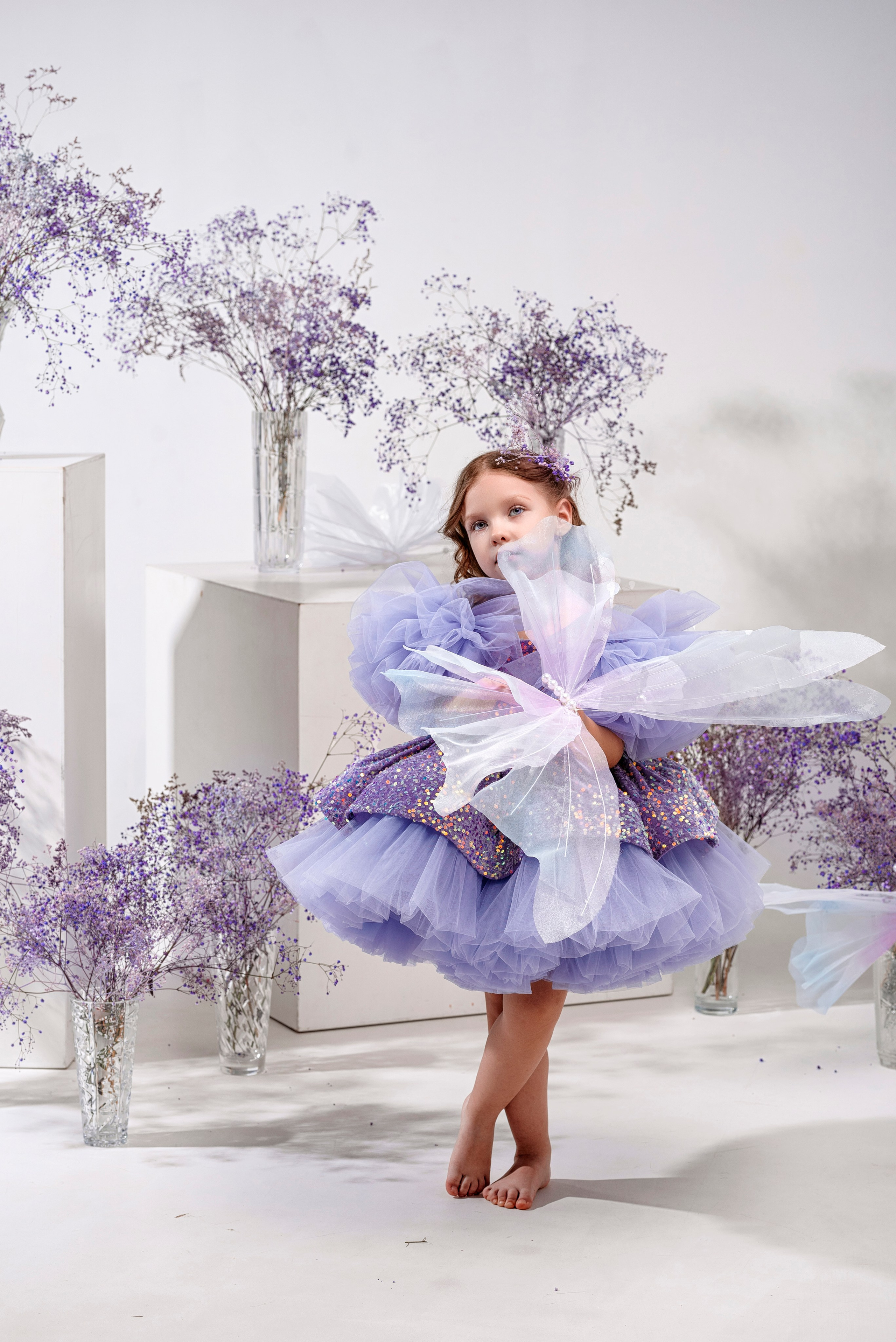 девочка в фиолетовом платье в фотостудии с гипсофилой и большой бабочкой