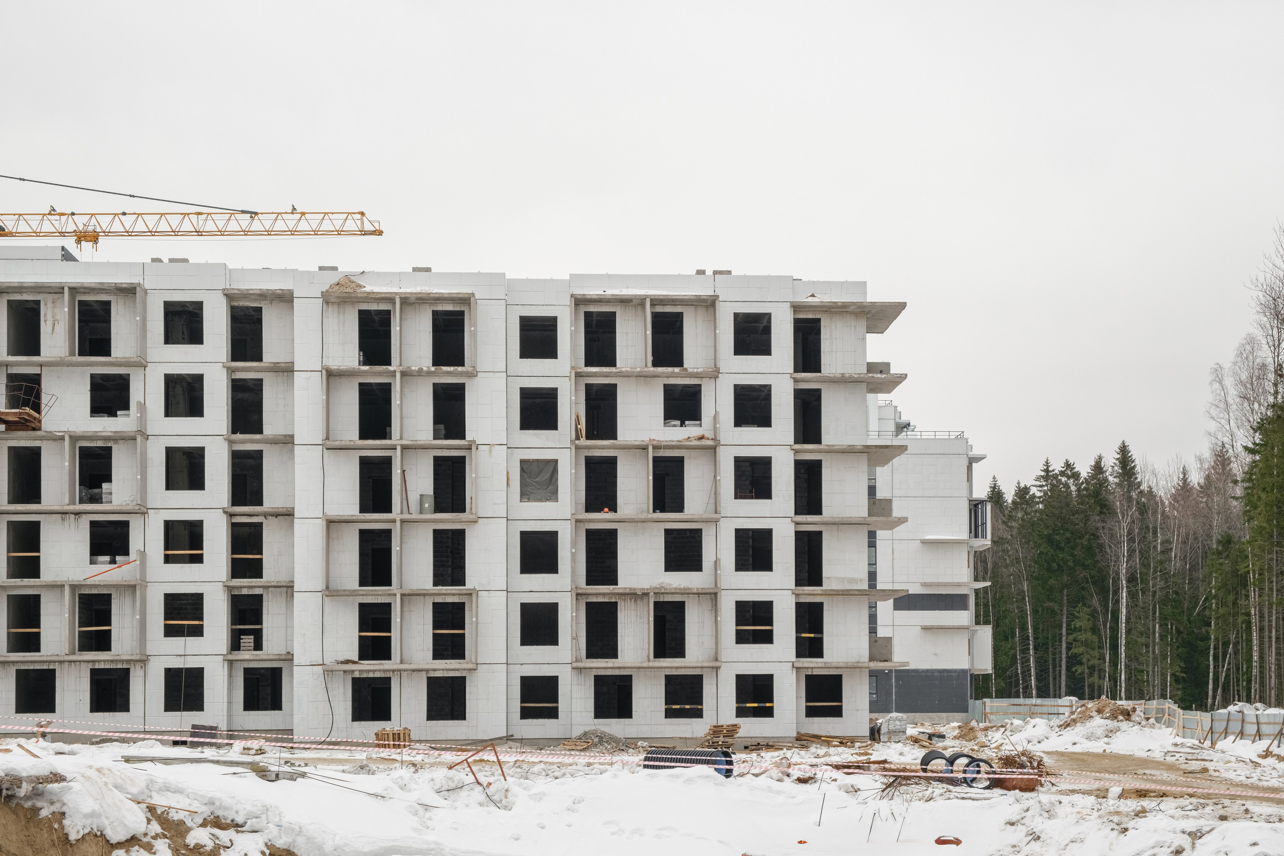 На изображении представлено здание в процессе строительства. Здание высокое, с множеством этажей и большими окнами. Вокруг здания видны строительные леса и другая инфраструктура стройплощадки.