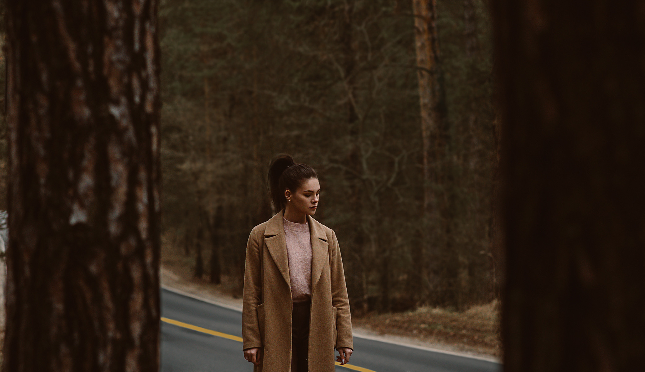 Девушка на проселочной дороге среди сосен. Съемка в стиле кино. Темная обработка