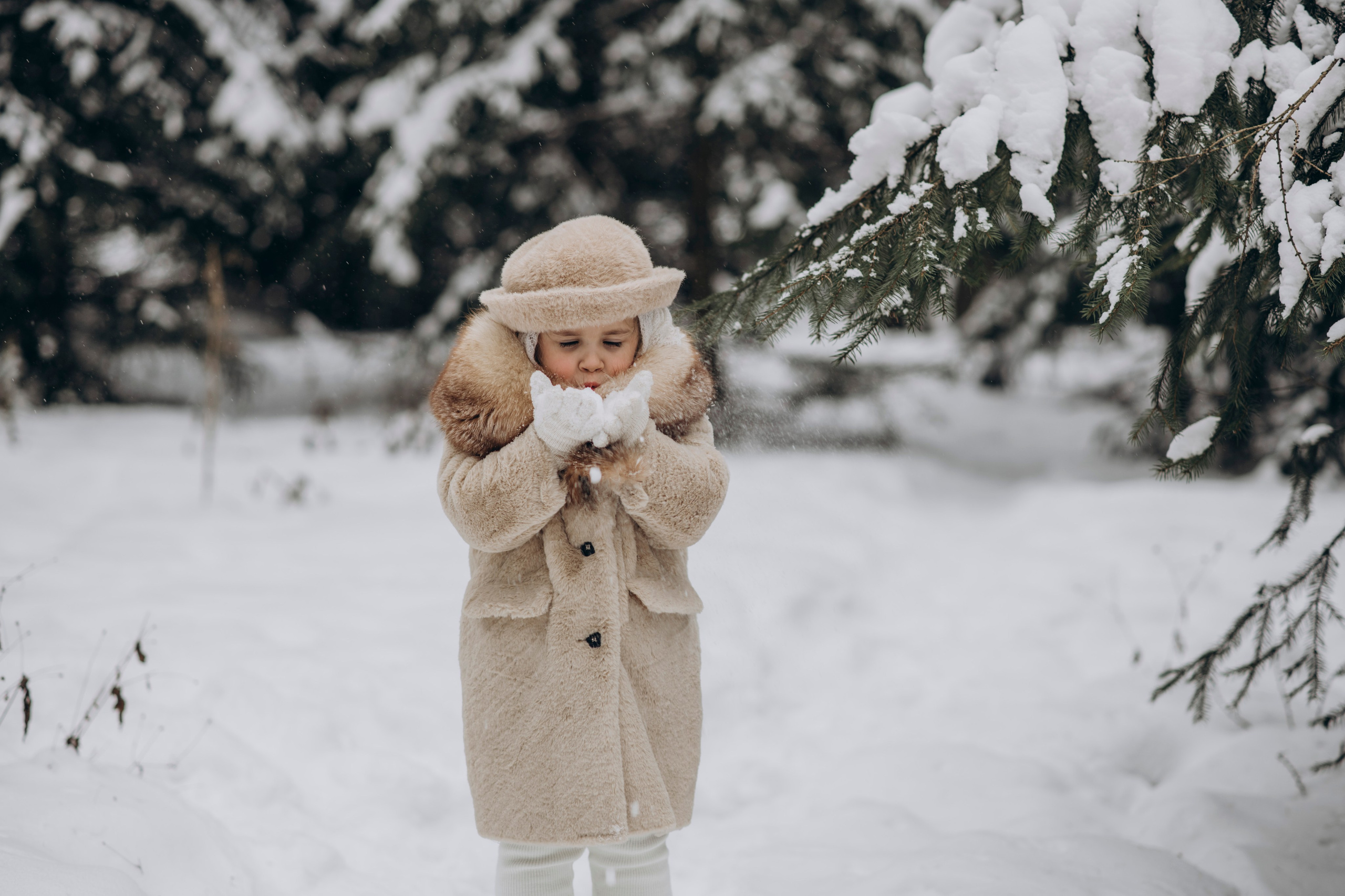 Детская фотосессия зимой, девочка дует на снег