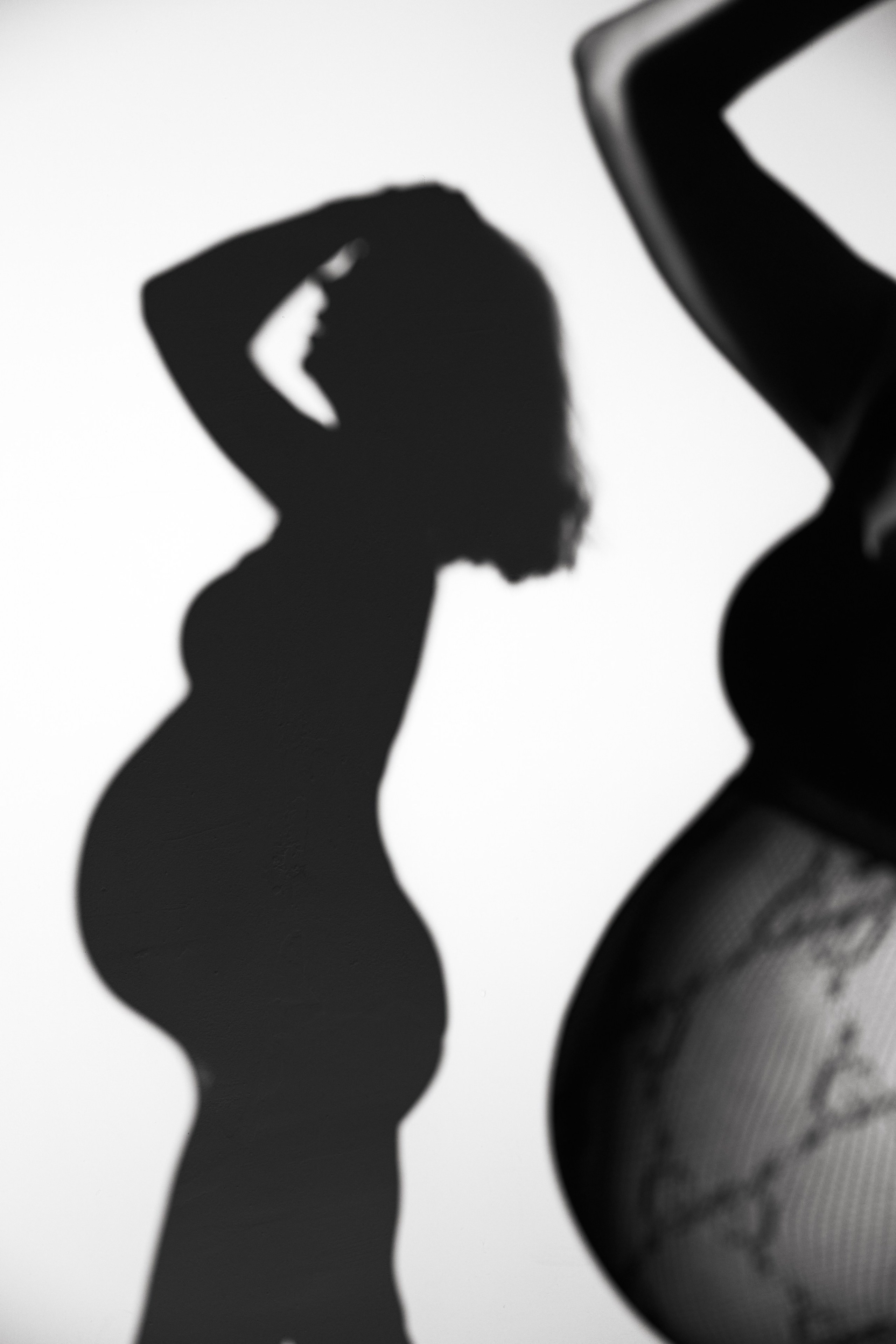 Тень беременной девушки, изображенная в элегантном фэшн-стиле с элементами будуарной эстетики. Фотография подчеркивает изящные линии силуэта, мягкий свет и атмосферу уюта, создавая вдохновляющий и чувственный образ. Идеально для тематики моды, материнства и художественной фотографии.