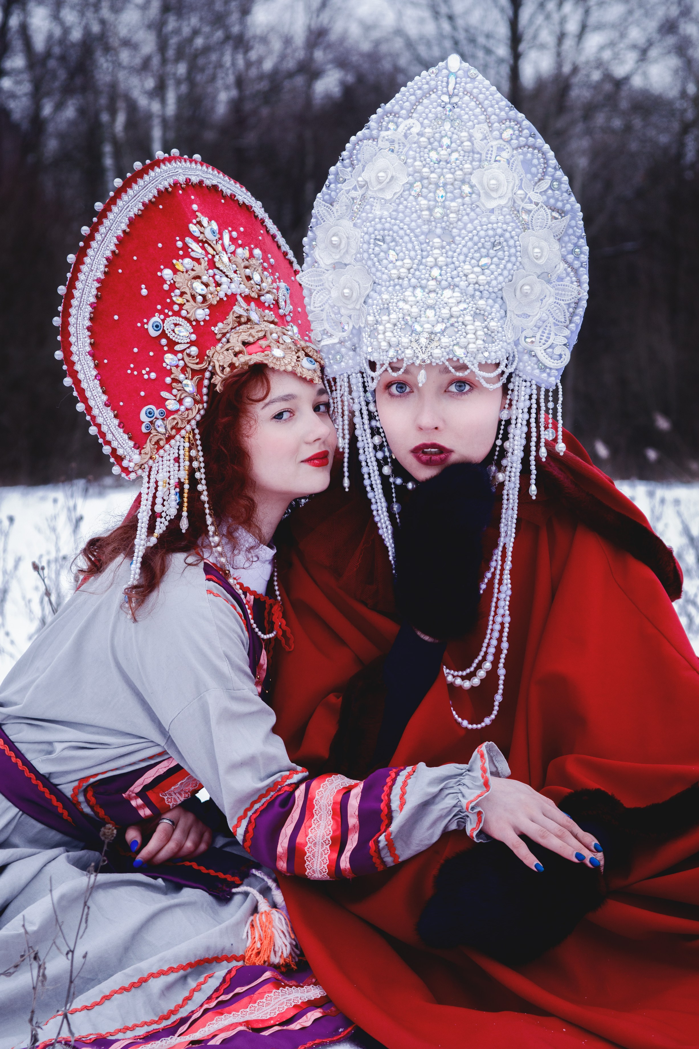 Две девушки в лесу зимой в русских народных костюмах на масленицу 