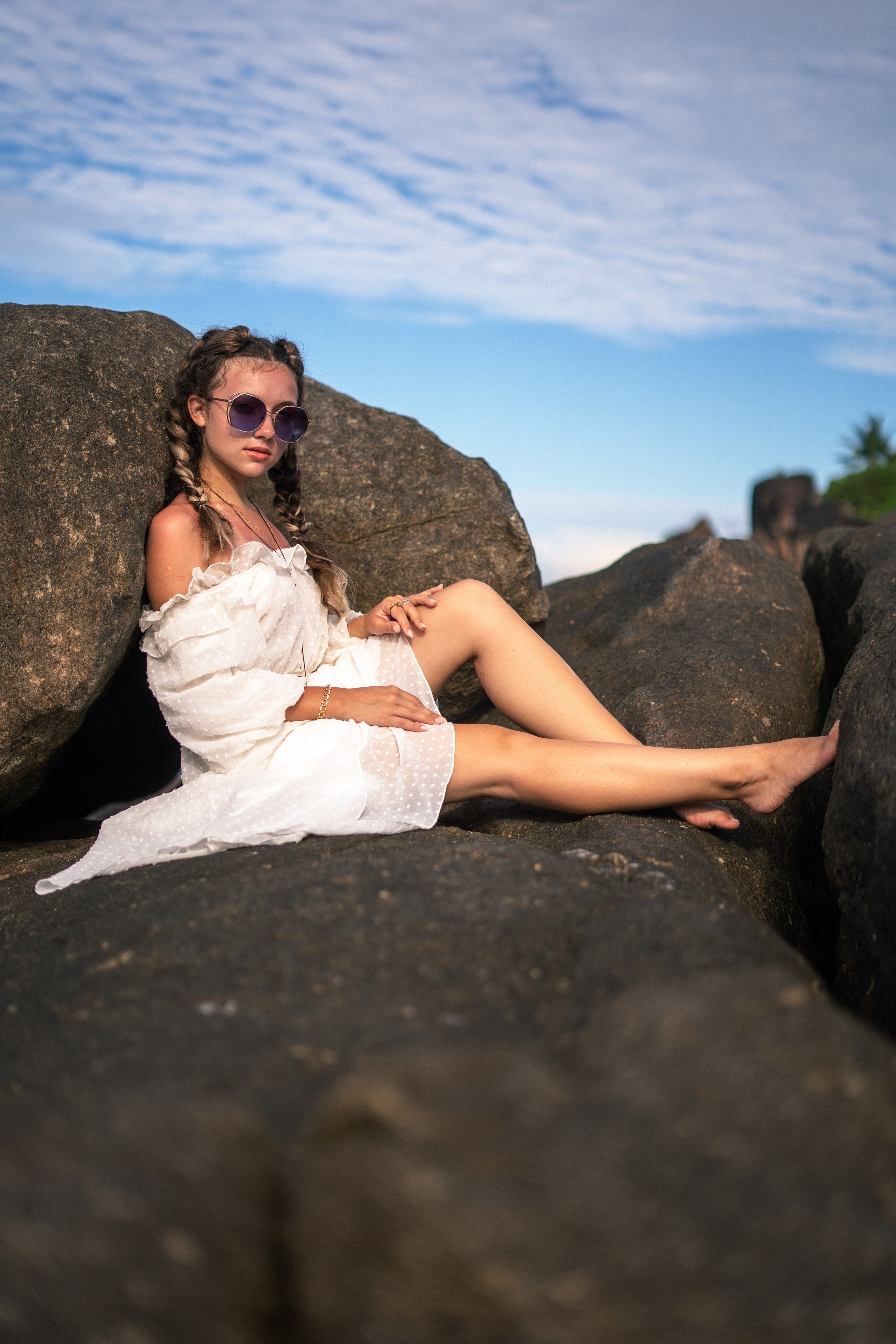 a young beauty in a white dress and glasses against the backdrop of ocean waves