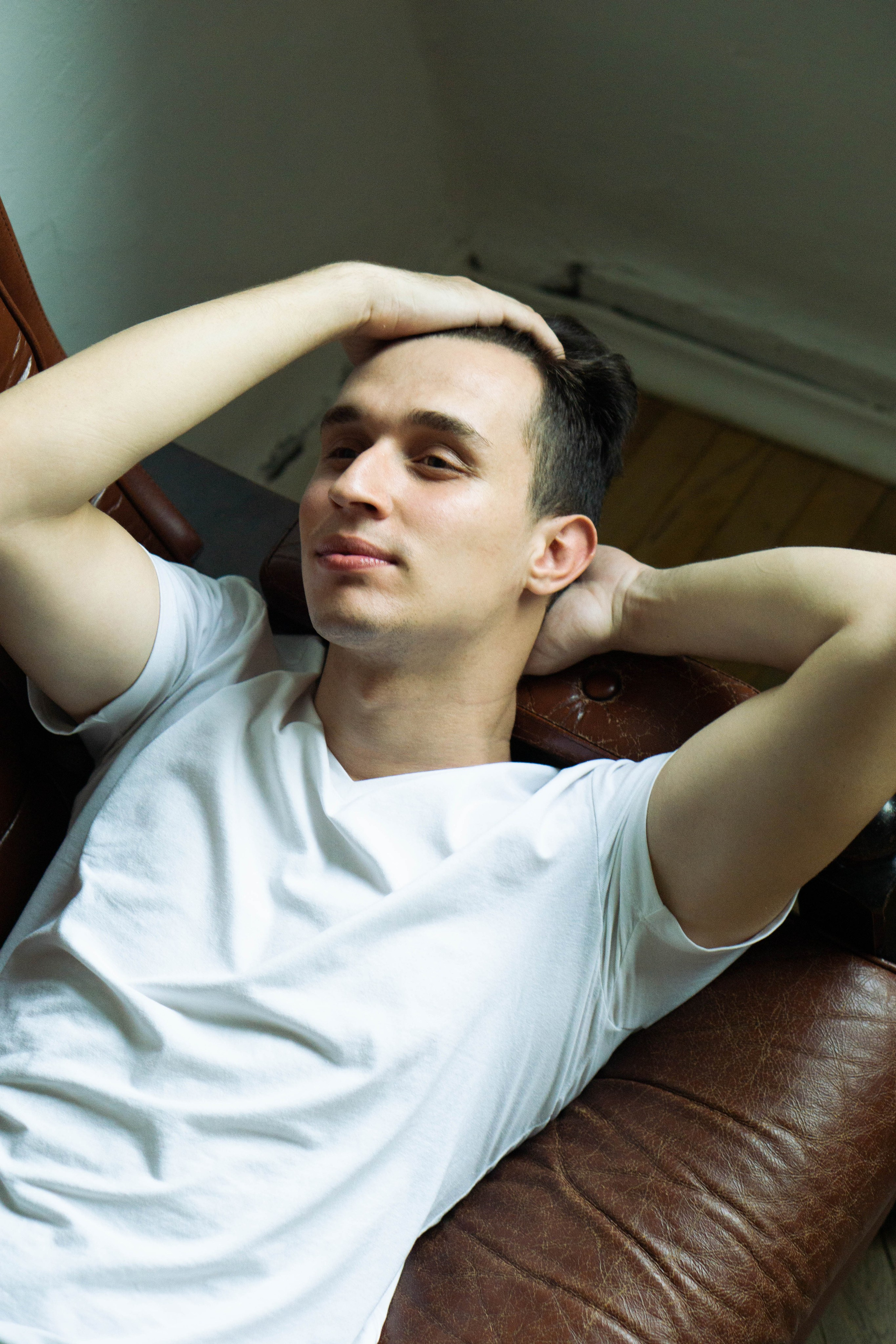 портрет мужчины в белой футболке поправляющего волосы 