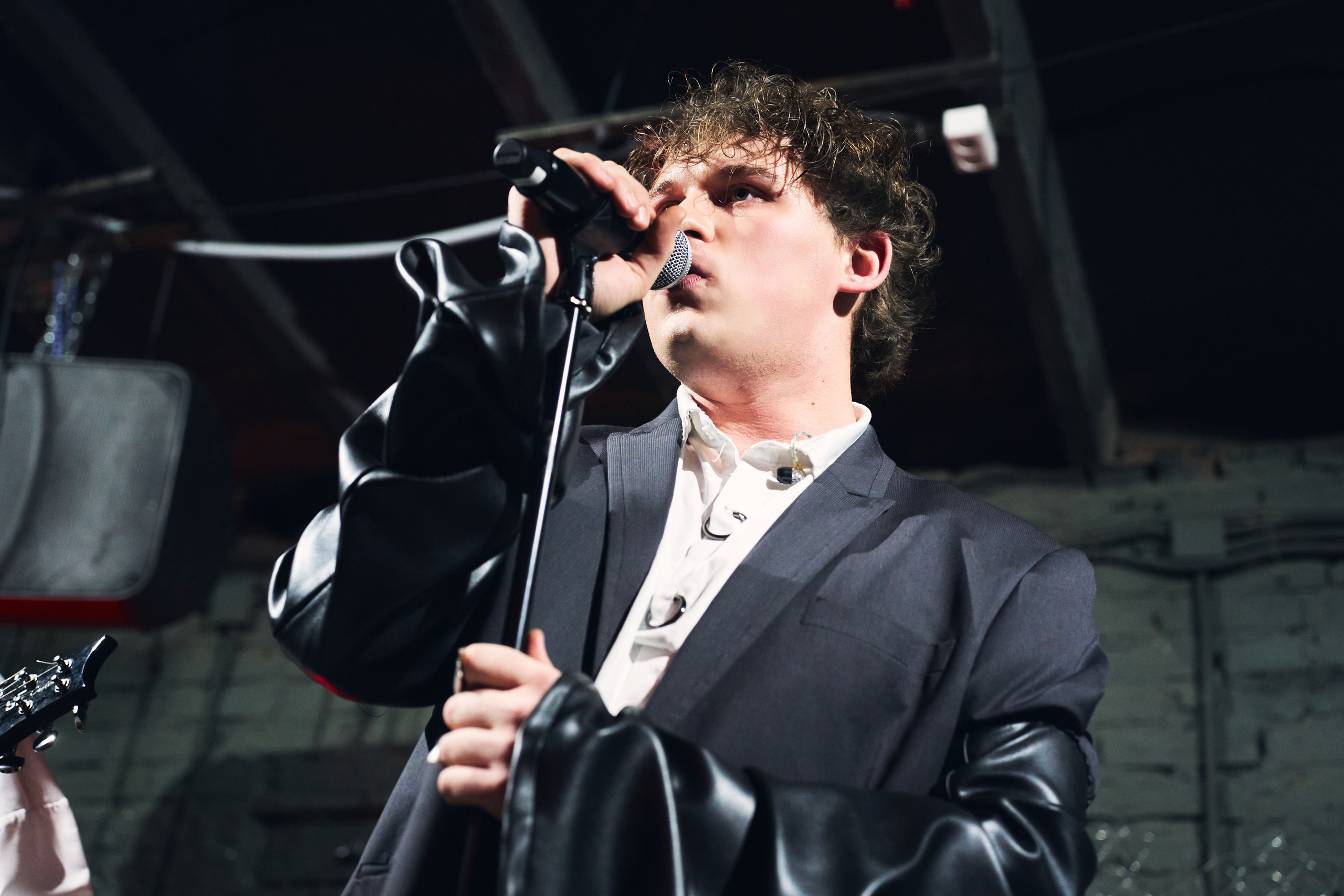 Вокалист ЙОЛО выступает с микрофоном на сцене, крупный план, концертный свет