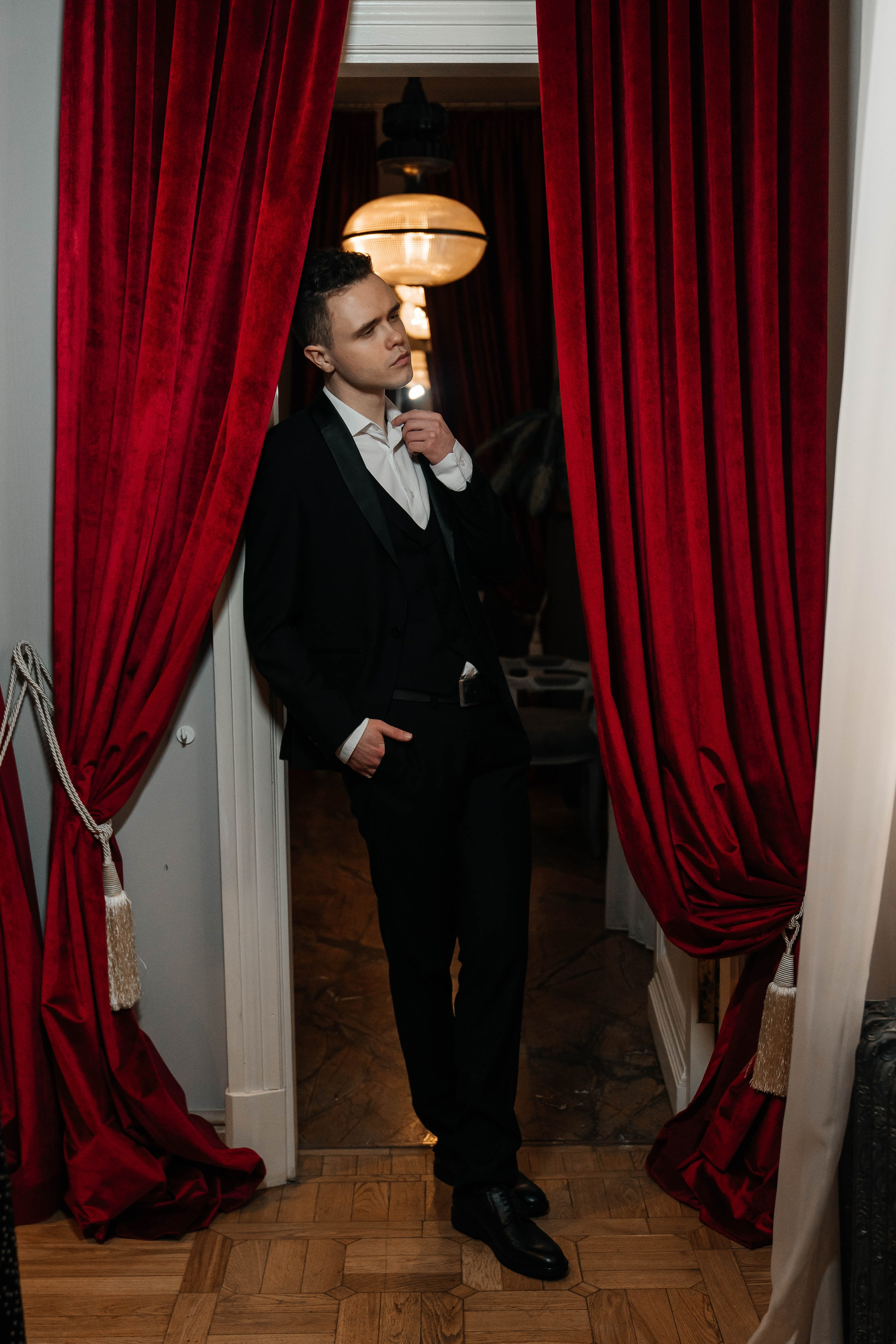 Жених в костюме на фоне красных штор