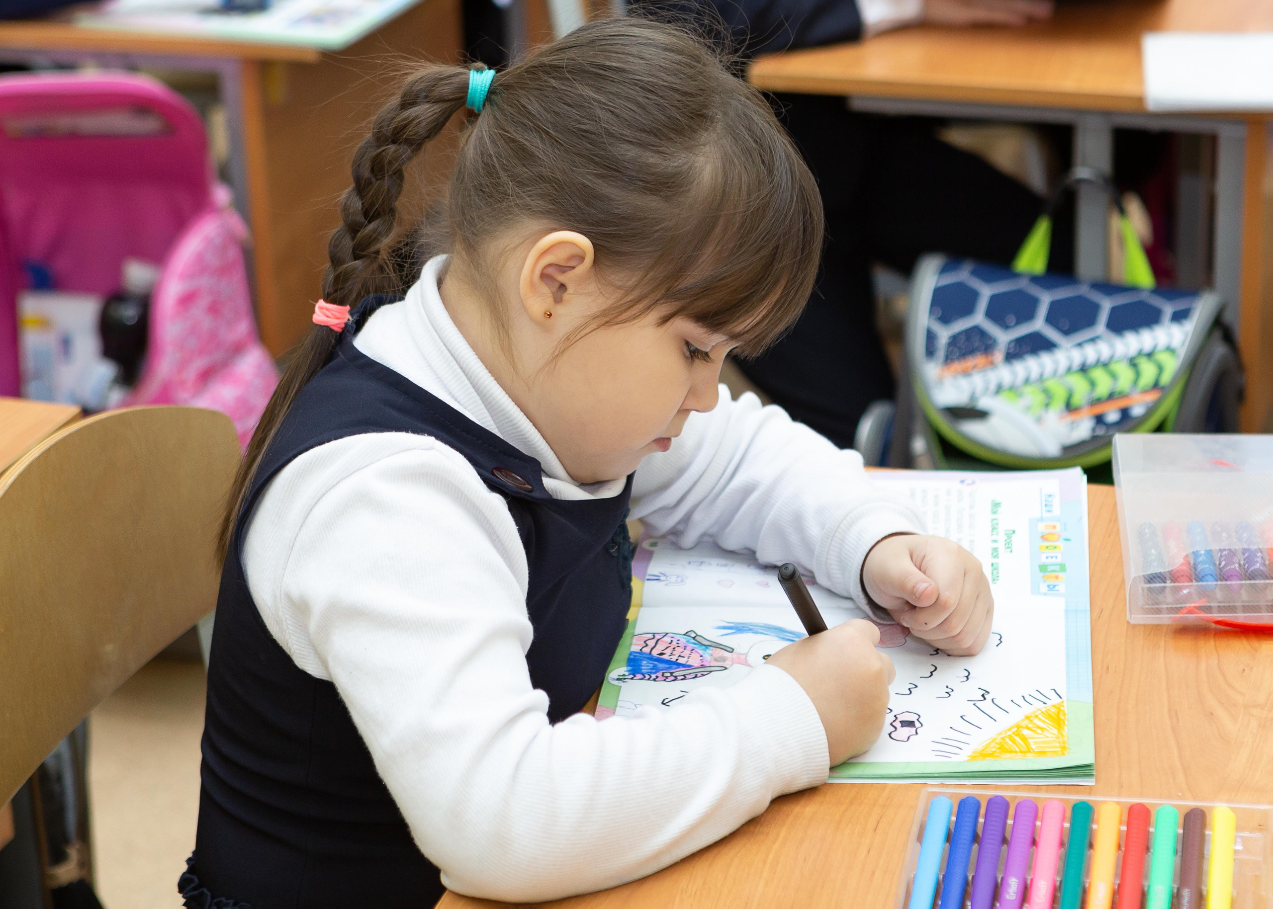 Девочка пишет в тетради на уроке