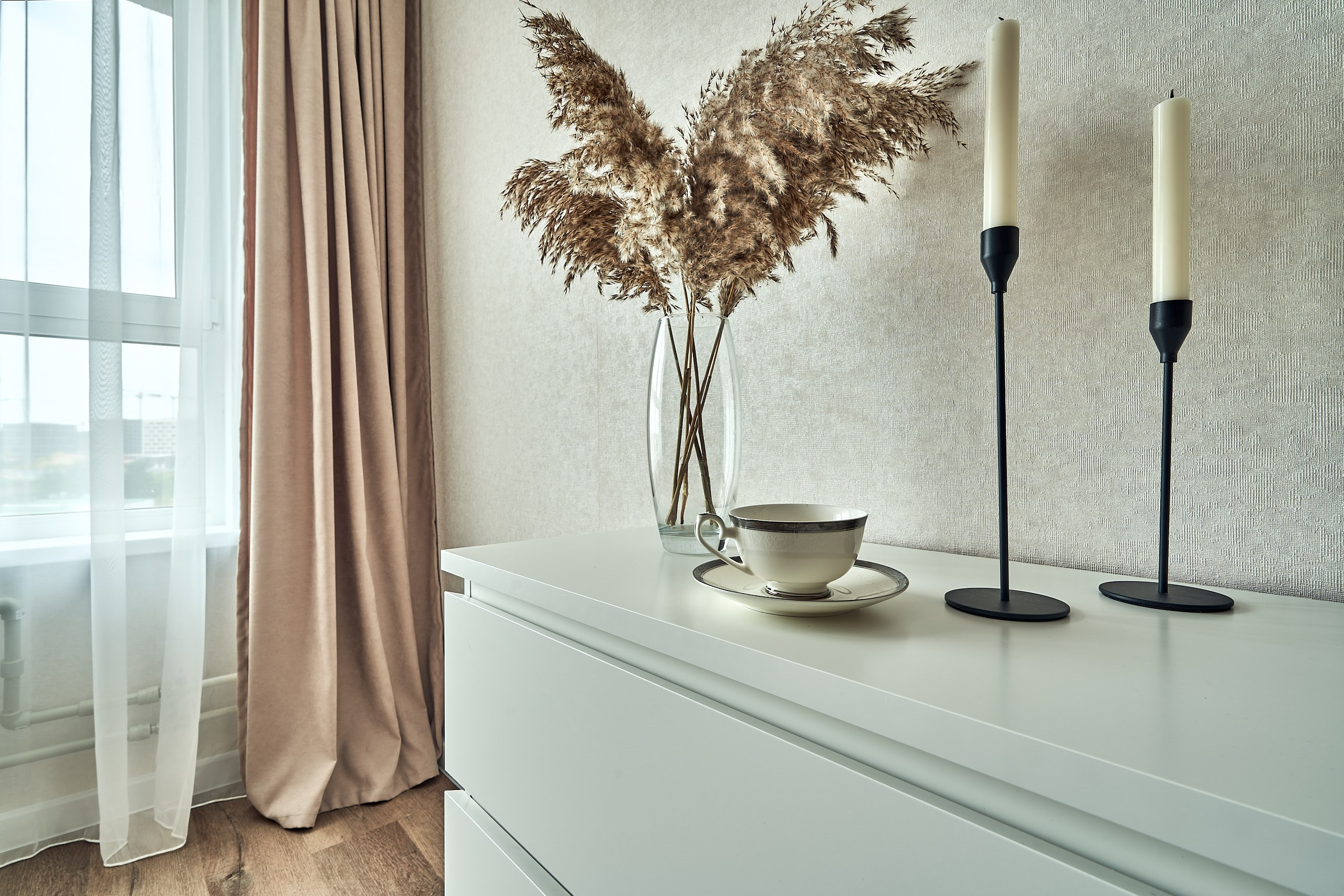 Интерьерное фото с окном, букетом и свечами на комоде в подмосковных апартаментах