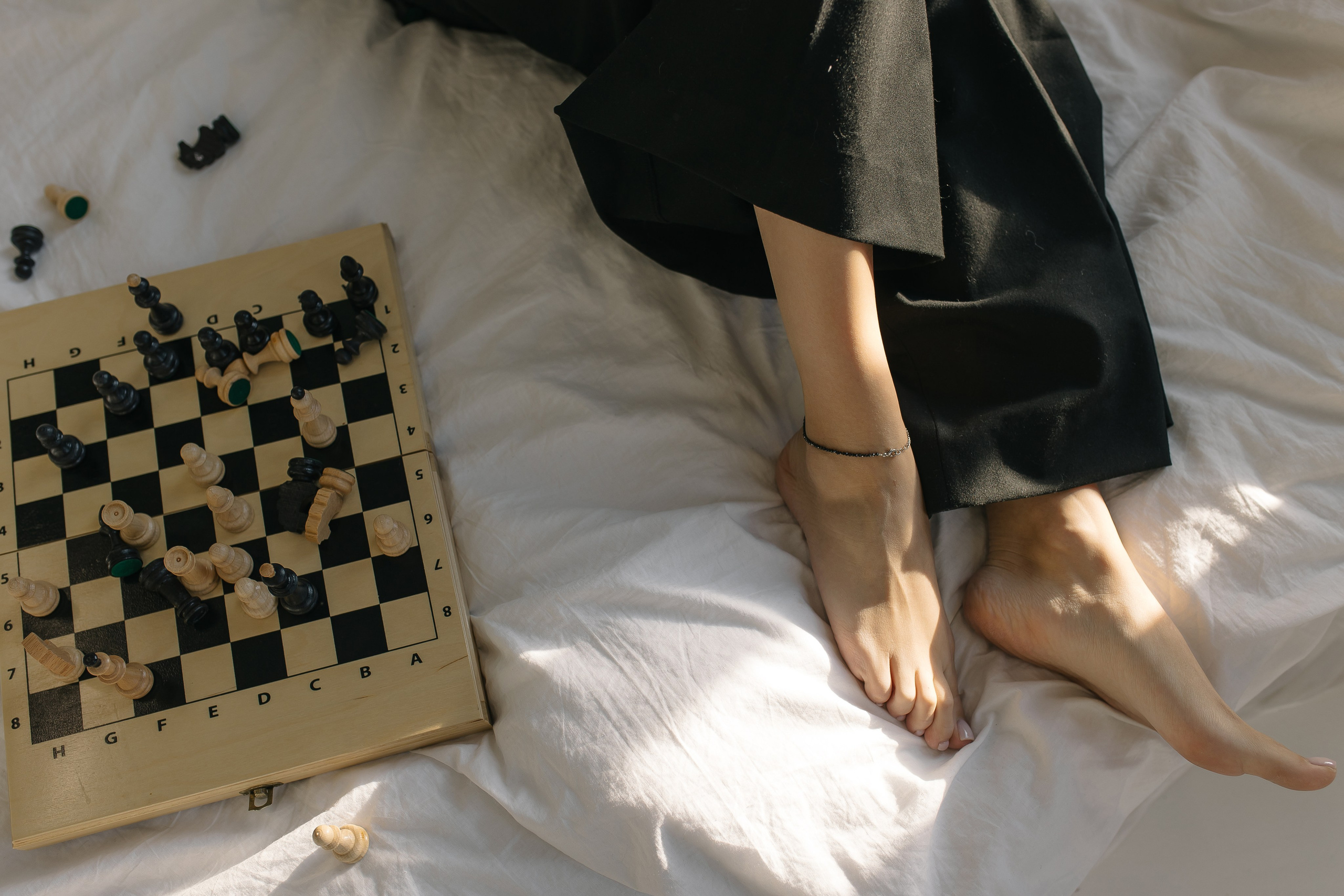 детали с фотосессии лав стори, где парень и девушка играют в шахматы на кровати