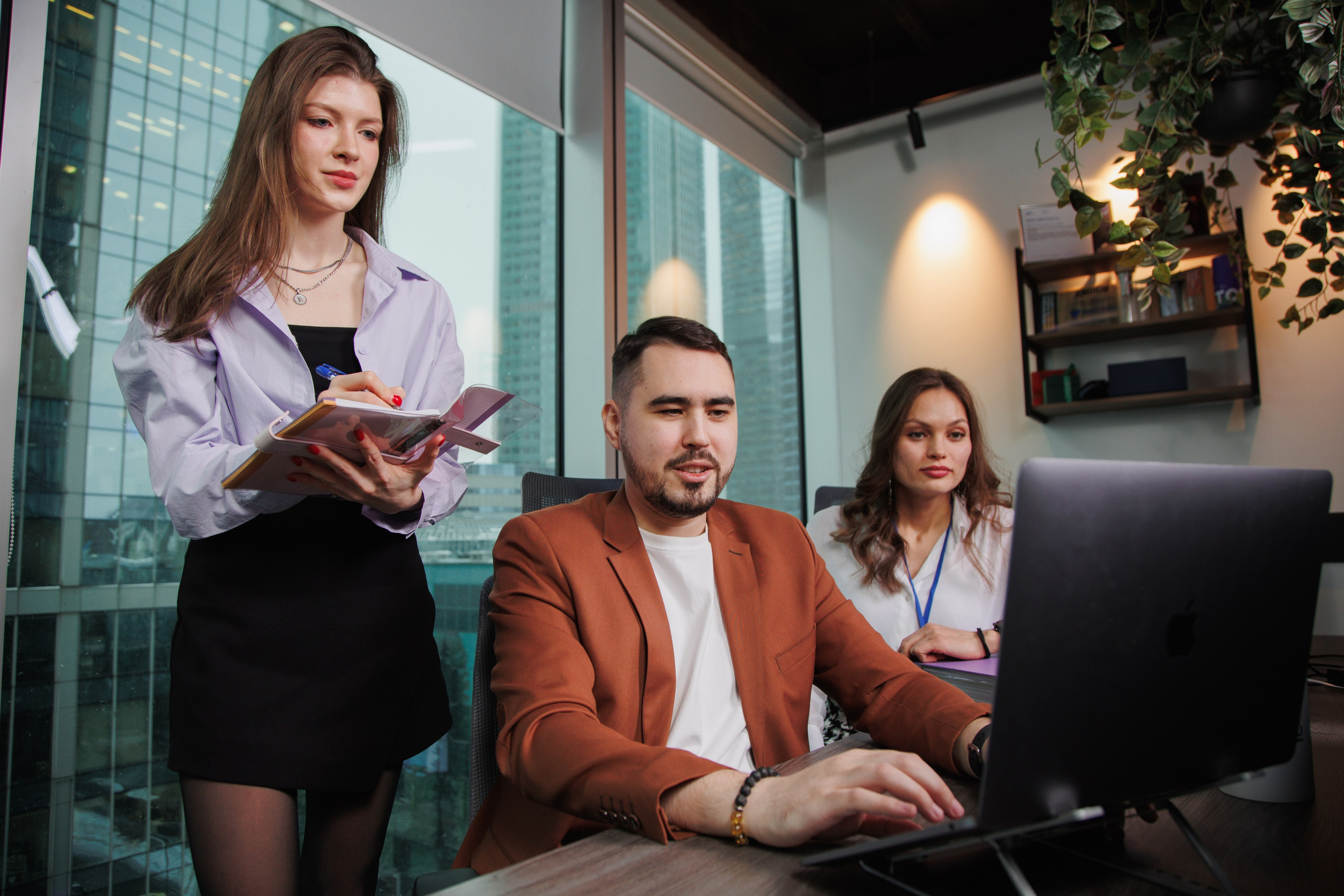 Трое инженеров обсуждают архитектуру проекта у монитора. Деловая фотосъемка в IT-компании.