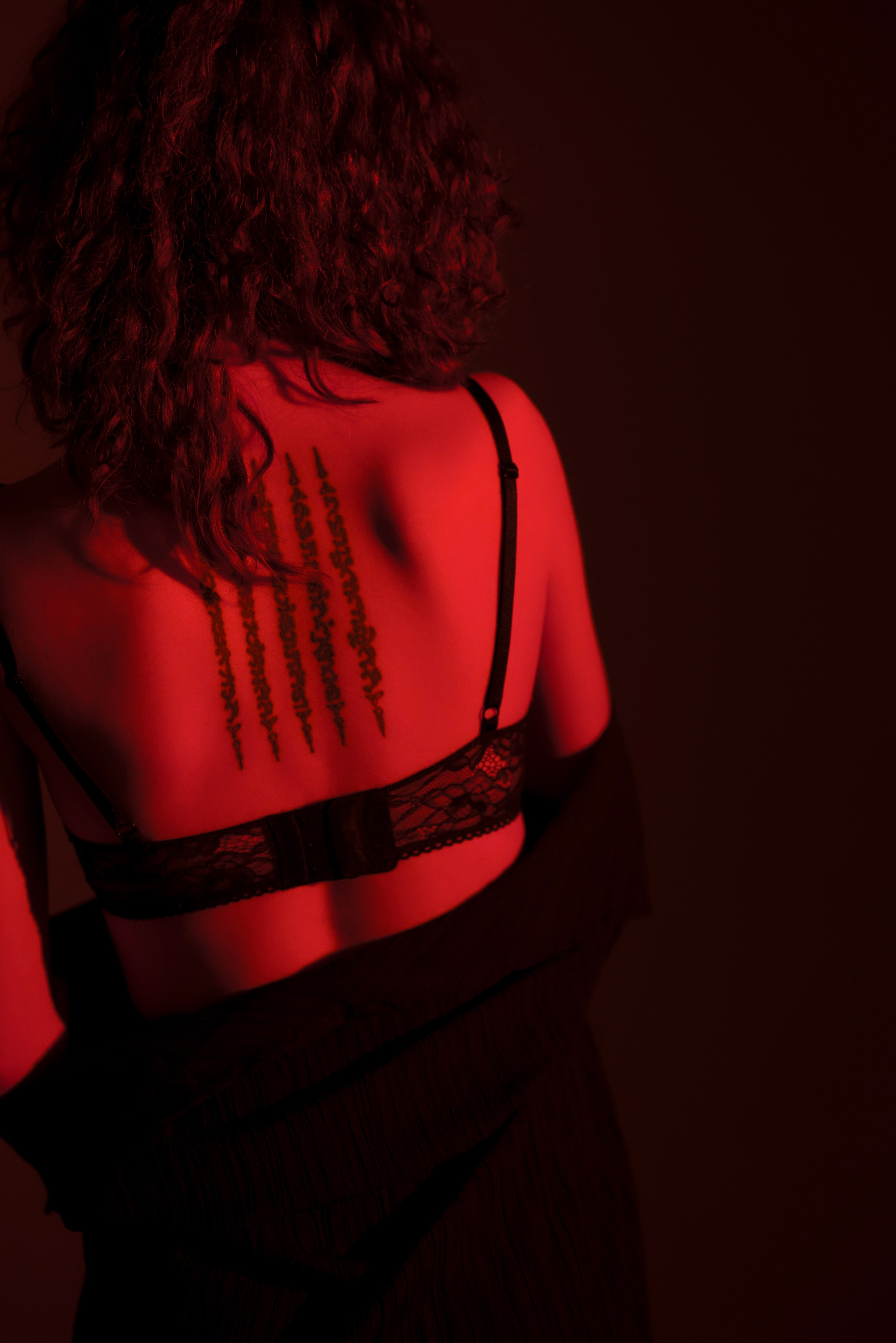 Спина девушки с татуировкой в красном свете