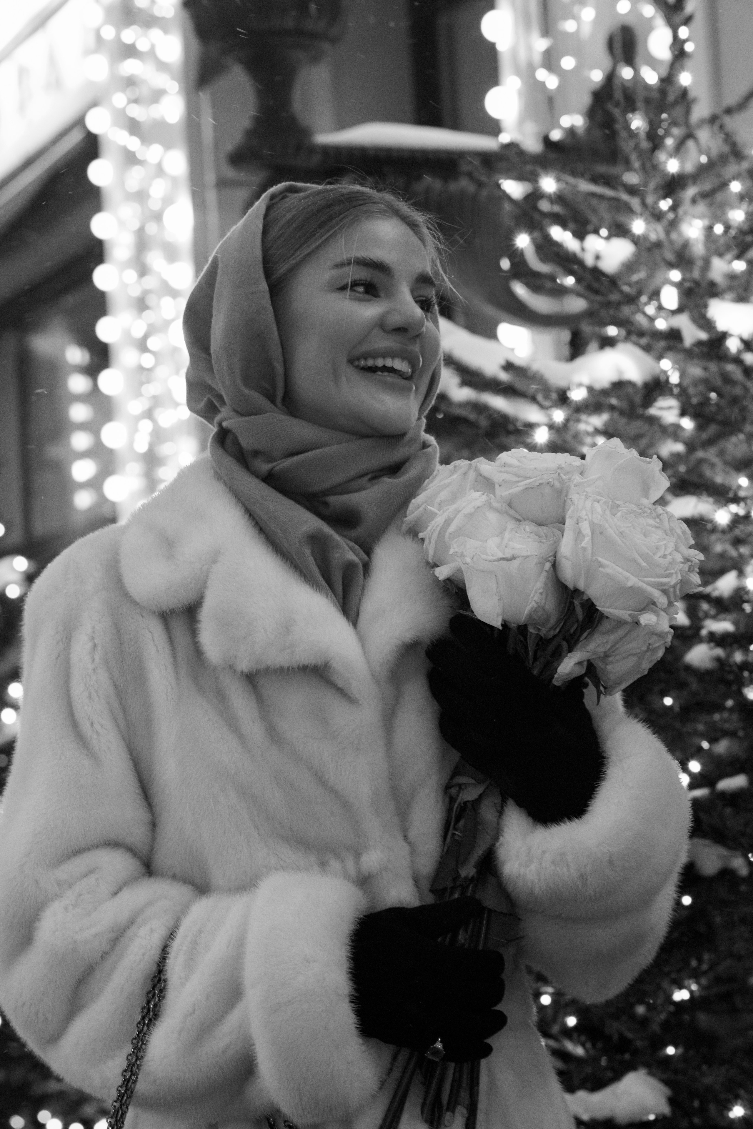 Девушка держит белые розы на черно - белом снимке зимой