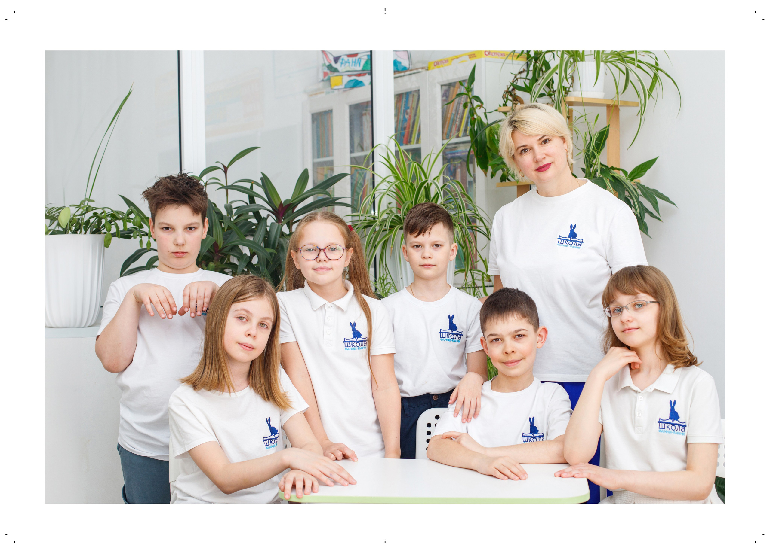 Групповой портрет четвероклассников со своим учителем в светлом классе.