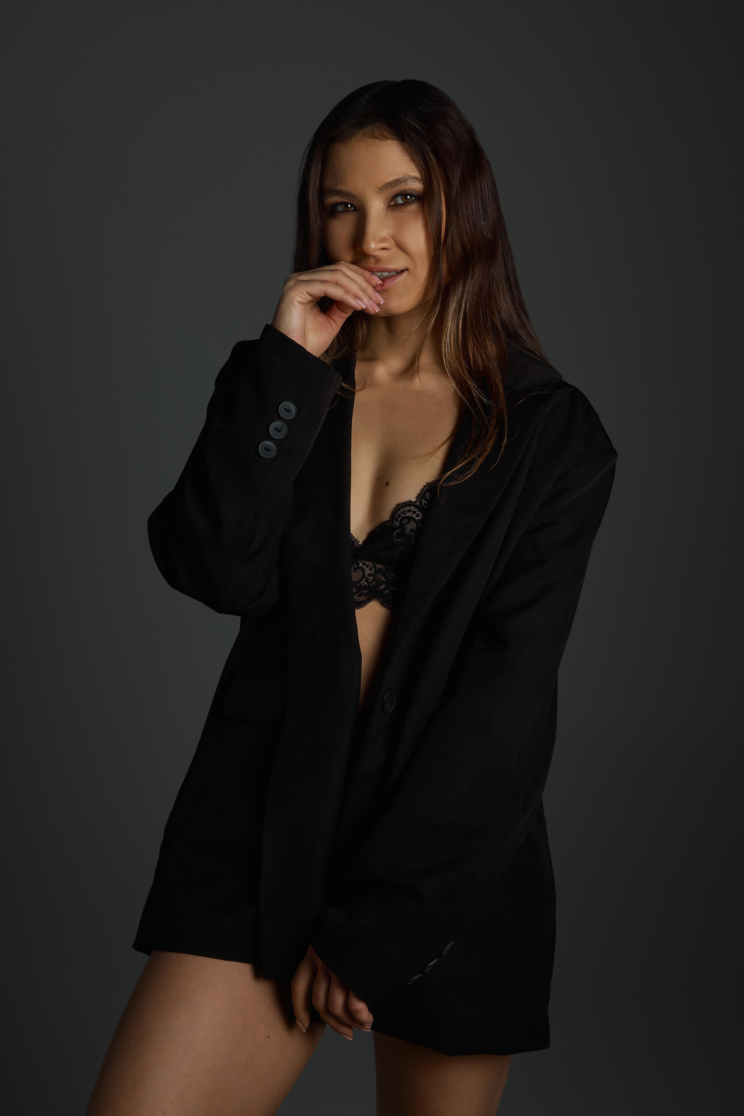 Девушка в черном пиджаке в фотостудии на сером фоне