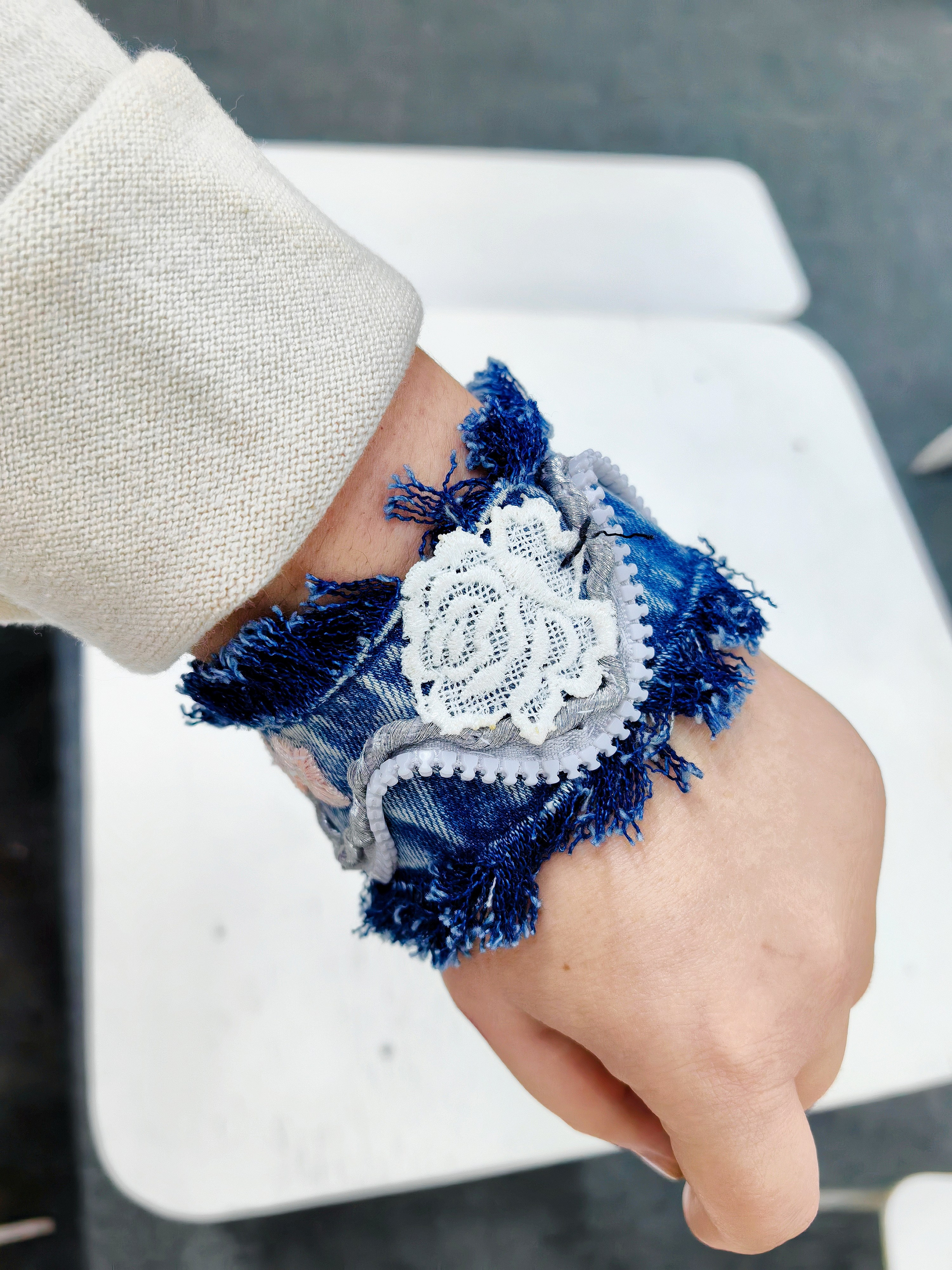 Джинсовый браслет, сшитый своими руками на мастер-классе по шитью и дизайну, демонстрирует девочка 8 лет.