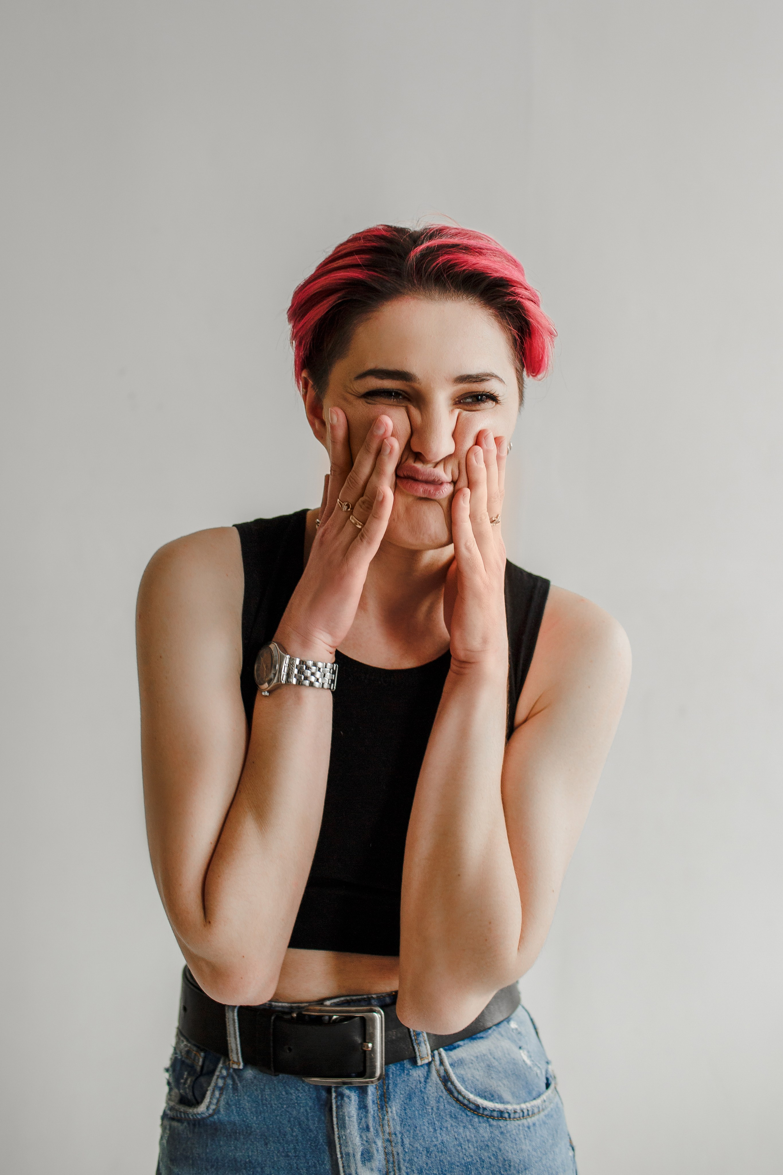 Девушка в фотостудии скорчила смешную рожицу, сжала щеки руками.