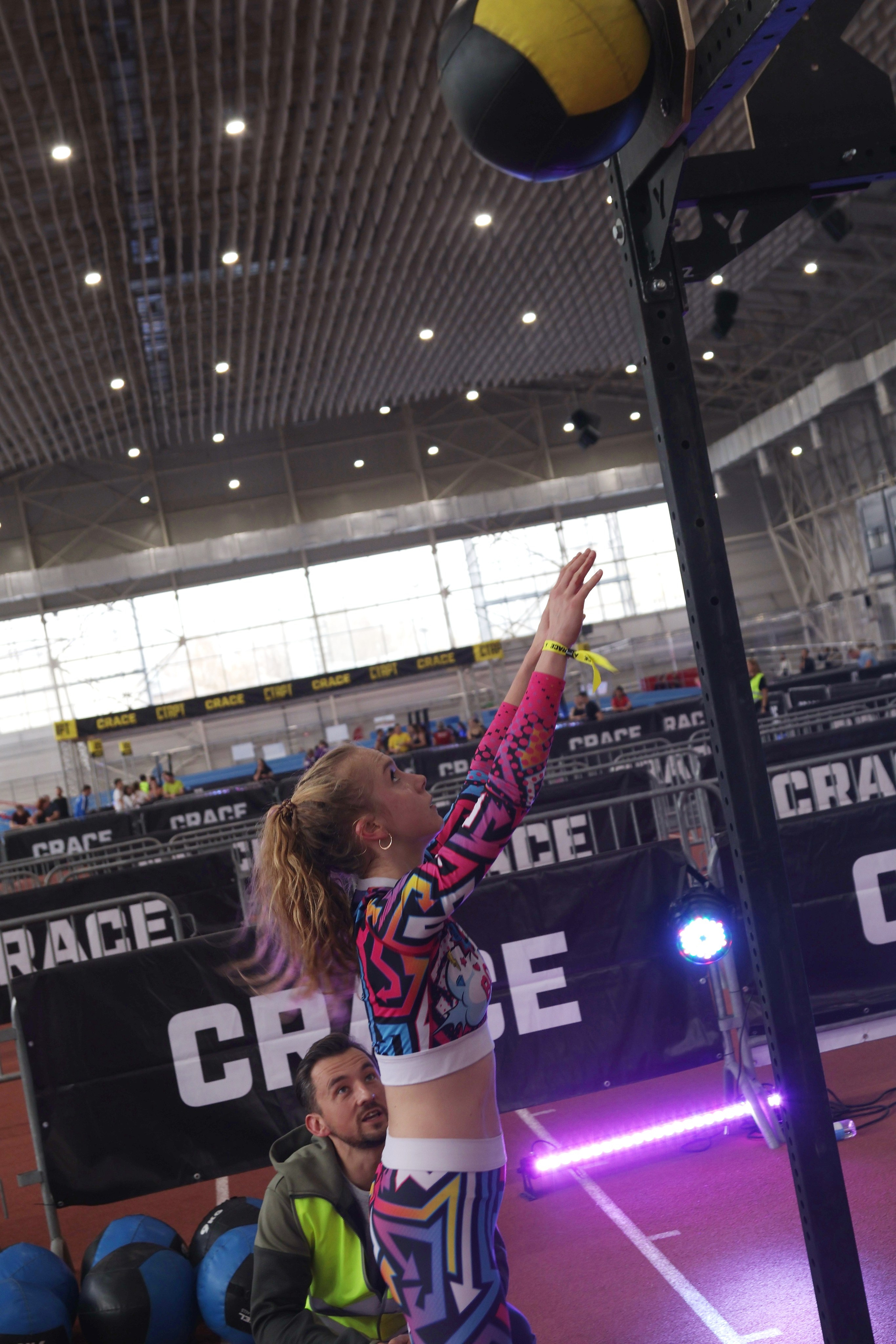 Девушка бросает мяч на соревнования по кроссфиту 