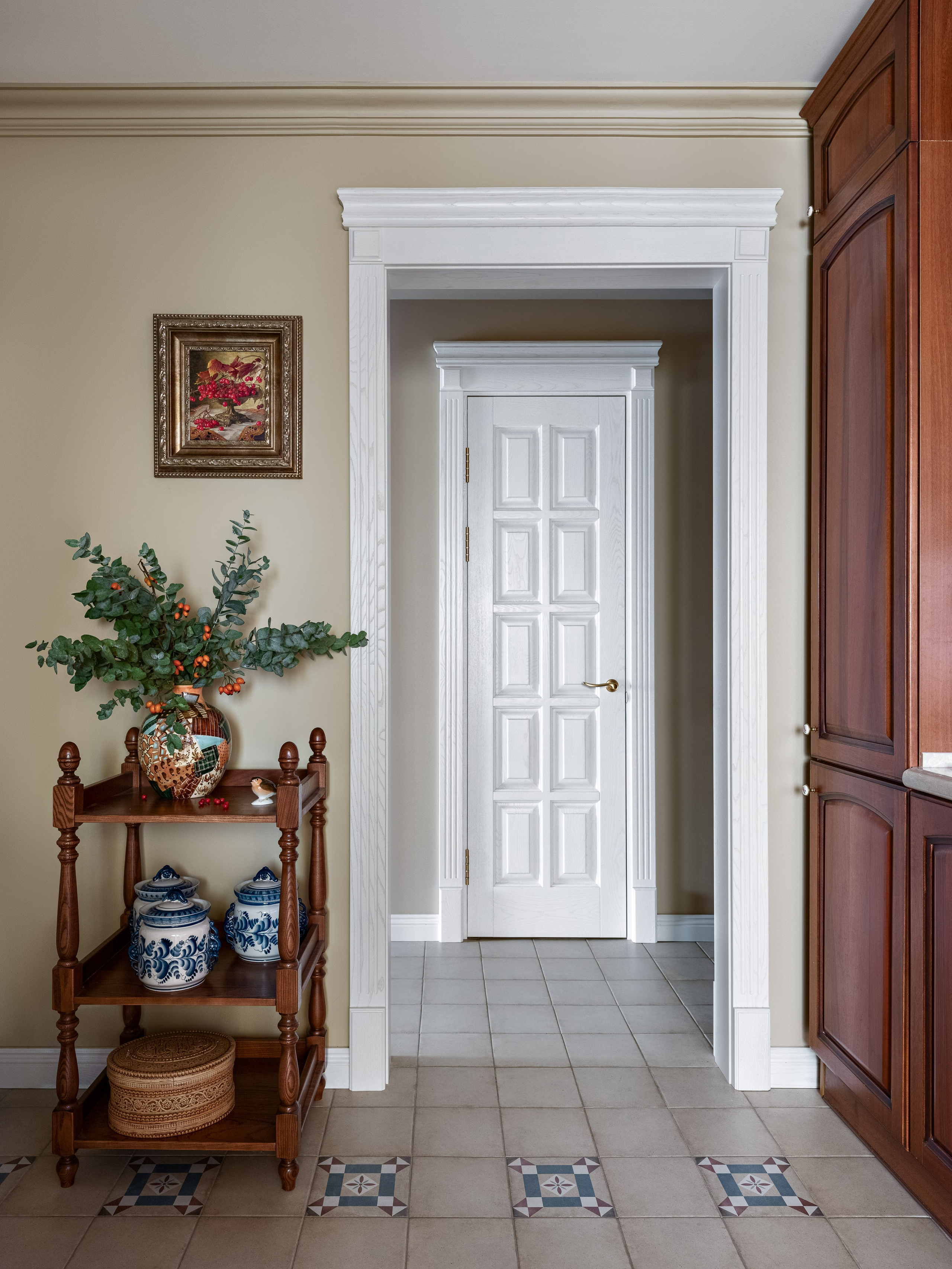 Дизайн кухни с белой дверью в декоративной арке, деревянной этажеркой с гжельскими вазами и декором из зелени и ягод. Фото подчеркивает атмосферу уюта и стиля. Авторский проект Юлии Капункиной и Альбины Терещенко, стилист Алина Нелень, фото Сергей Денисенко.