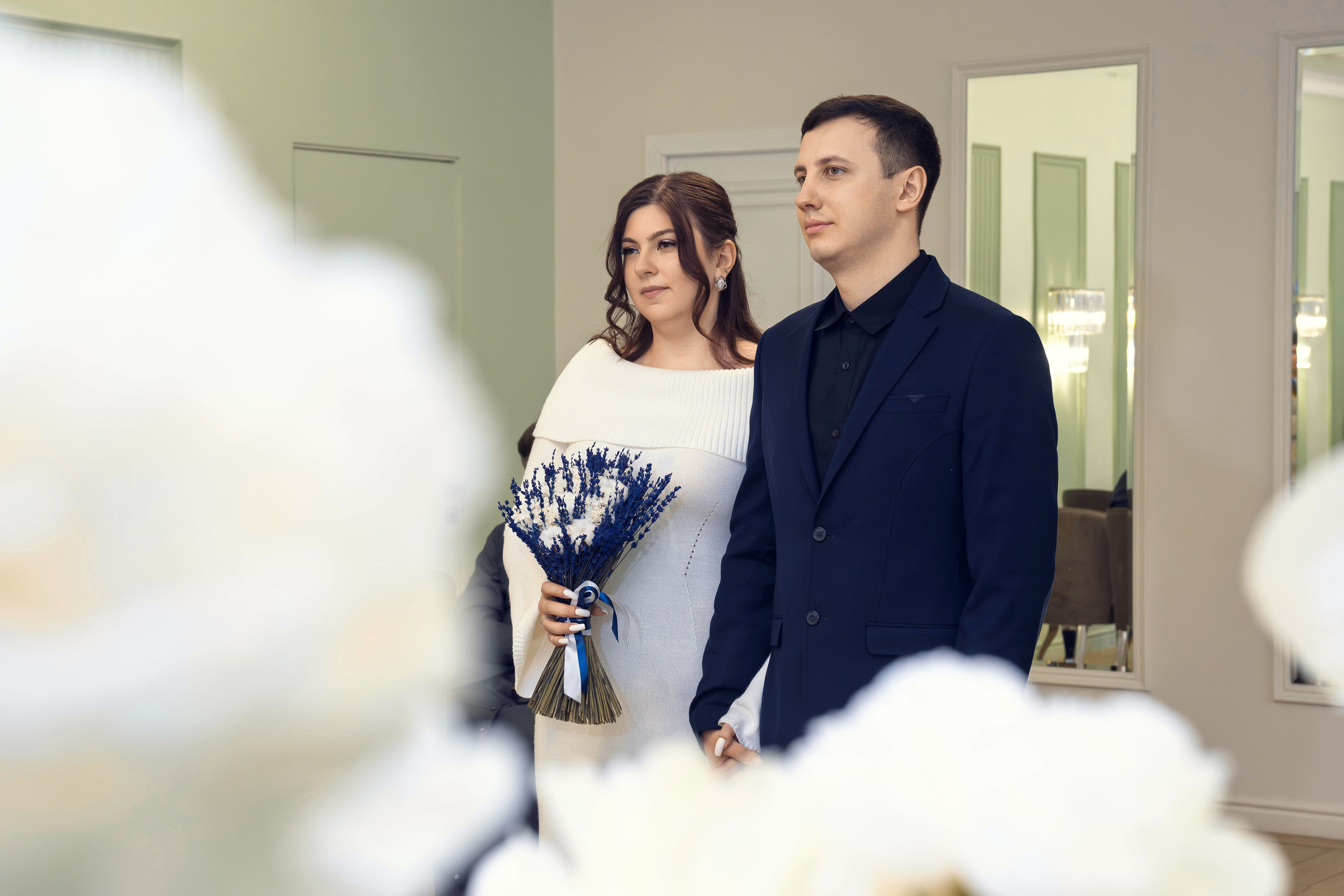 Жених и невеста обнимаются у ЗАГСа после регистрации. Невеста с букетом в руках во время церемонии в ЗАГСе. Обмен кольцами на регистрации брака в ЗАГСе. Первый поцелуй молодожёнов после регистрации в ЗАГСе. Подпись в книге регистрации брака крупным планом. Молодожёны держатся за руки в зале ЗАГСа. Выход молодожёнов из ЗАГСа под аплодисменты гостей. Свадебный портрет невесты в белом платье с букетом. Портрет жениха в костюме во время свадебной фотосессии. Совместный портрет молодожёнов на прогулке в парке. Невеста и жених идут по аллее, держась за руки. Молодожёны целуются на фоне городских улиц во время прогулки. Свадебная фотосессия в парке: жених поправляет фату невесте. Невеста смеётся, жених обнимает её со спины. Крупный план: свадебные кольца на руках молодожёнов. Детали свадьбы: букет невесты крупным планом. Невеста и жених на фоне архитектуры города во время прогулки. Молодожёны на закате: романтичный кадр со светом в контровике. Свадебная фотосессия у воды: пара смотрит друг на друга. Гости поздравляют молодожёнов у ЗАГСа, живые эмоции.