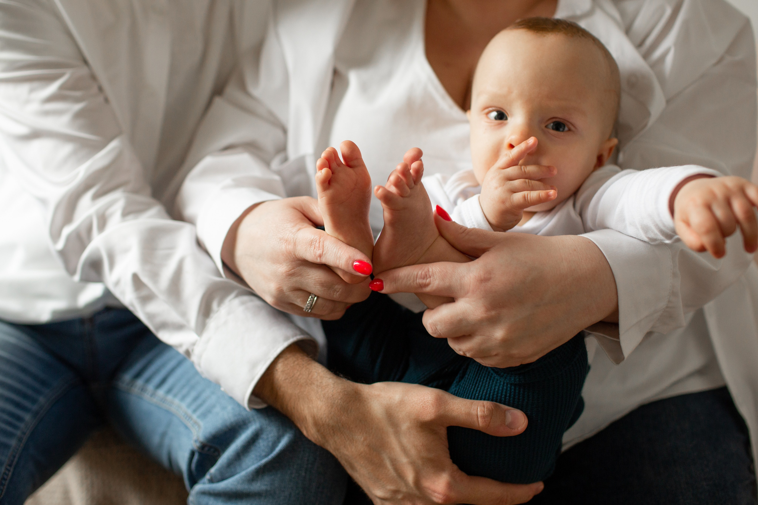 Нежная детская фотография: пяточки годовалого ребенка в руках родителей.