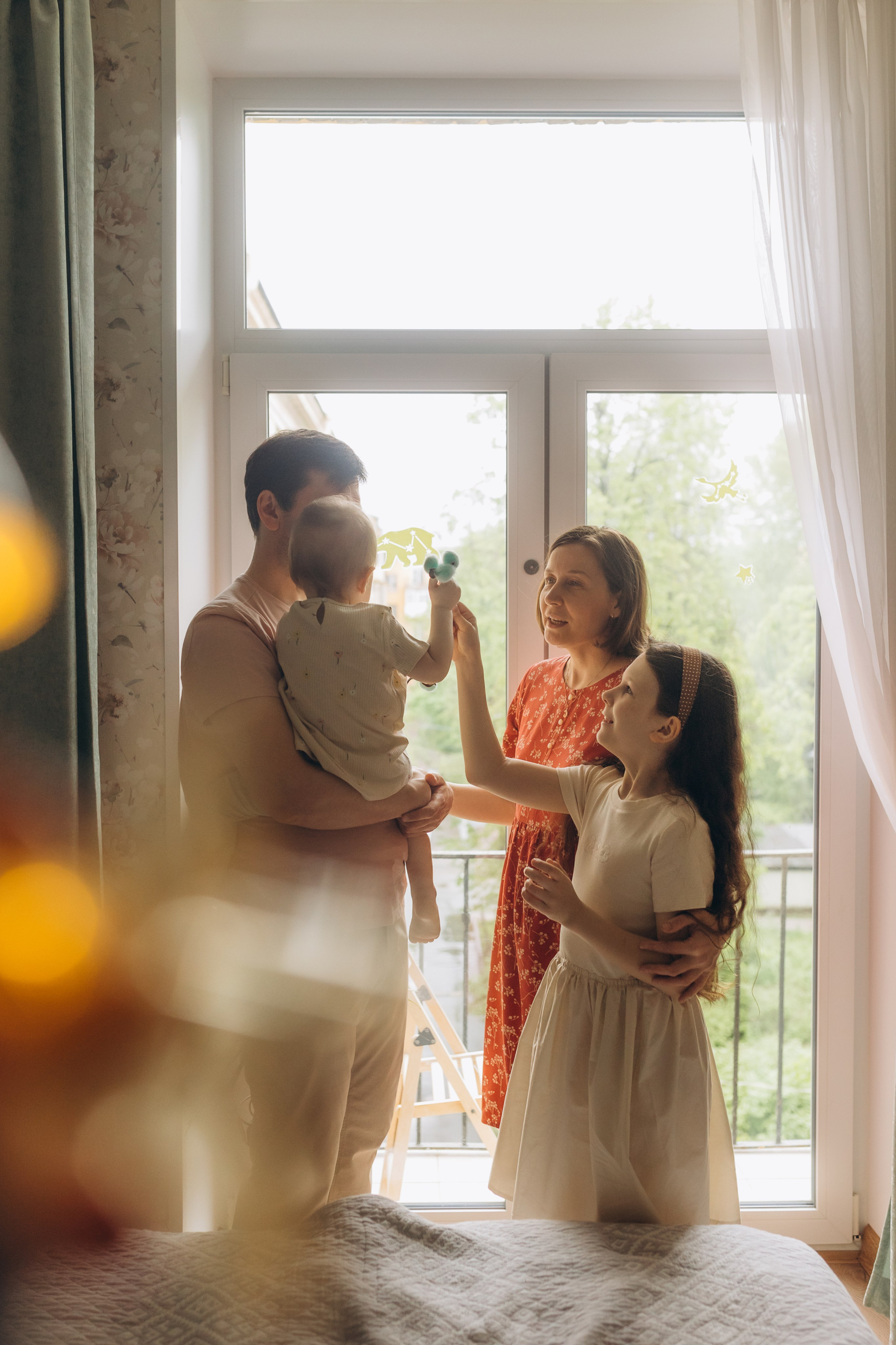 семья стоит у большого в пол окна