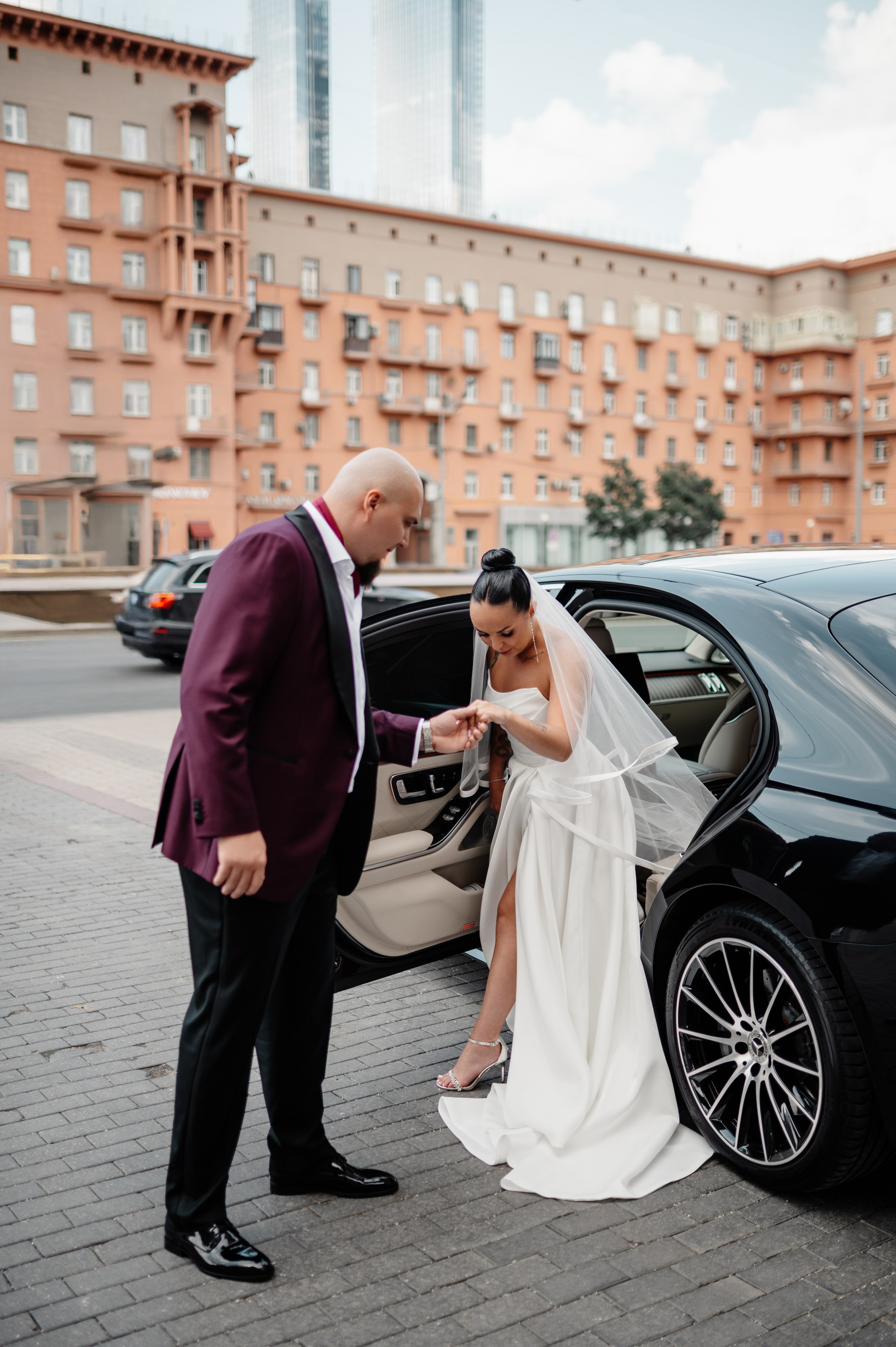 Жених помогает невесте выйти из машины.