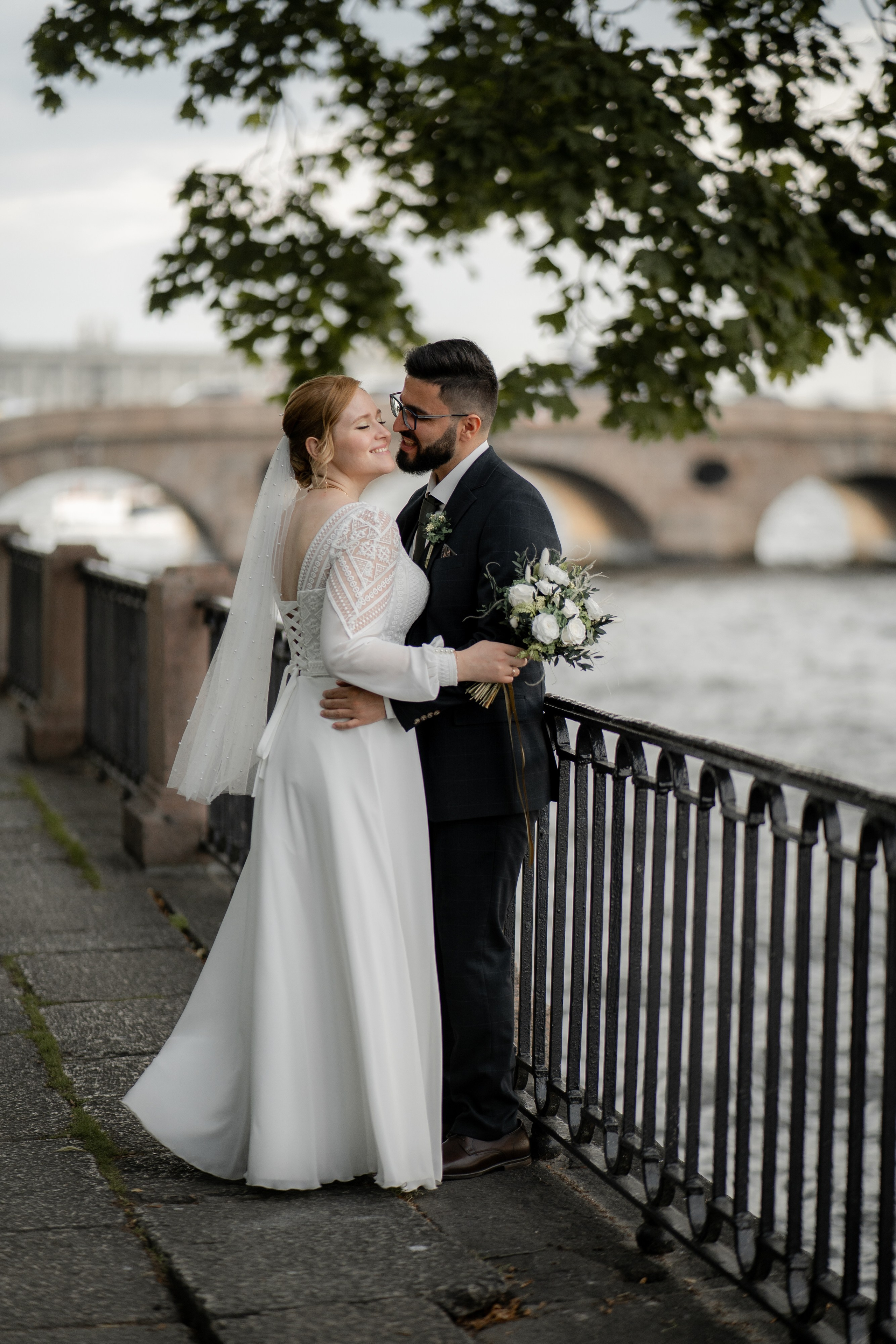 жених и невеста обнимаются на набережной в Летнем саду на свадебной фотосессии