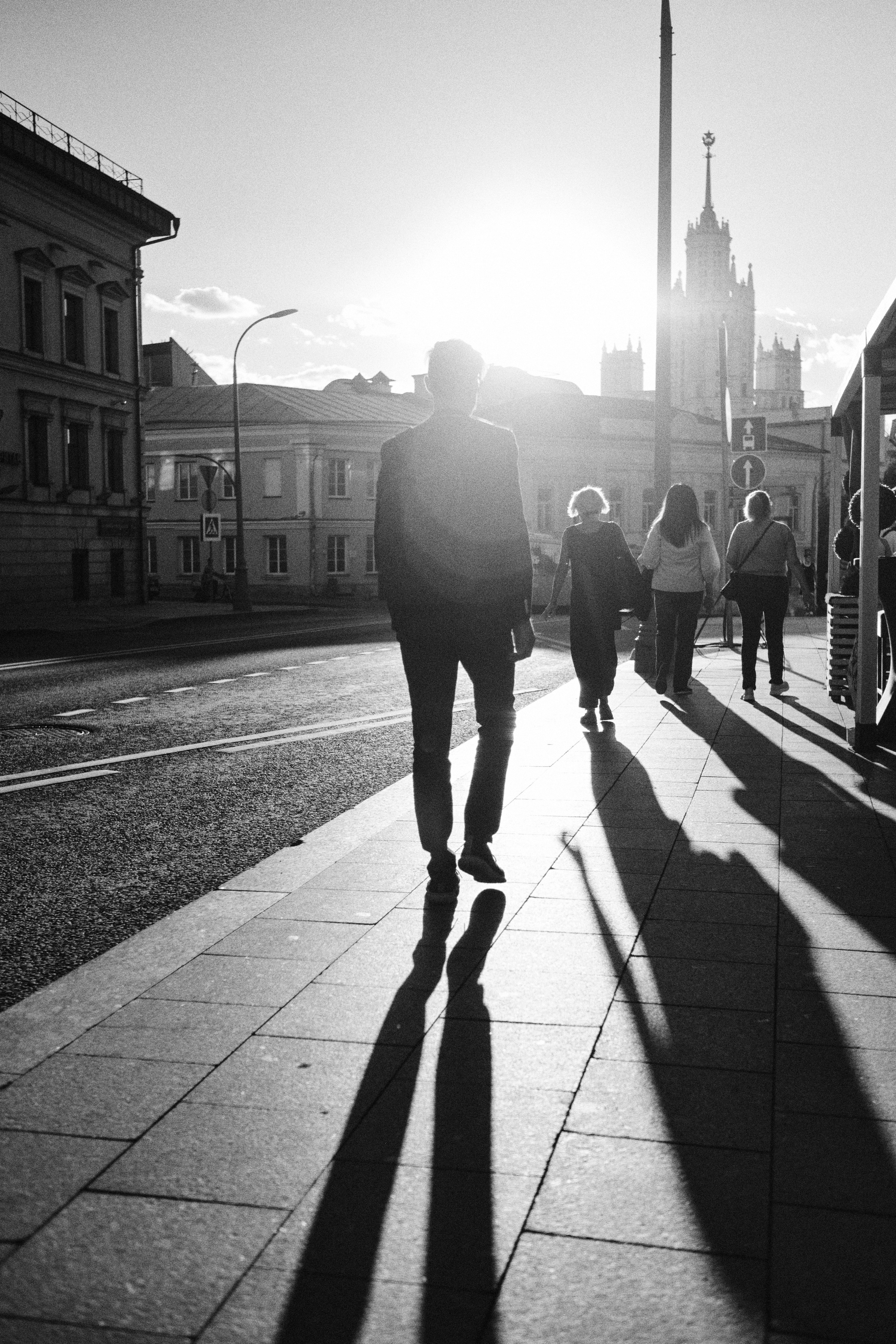 Длинные закатные тени, идущих по городу людей