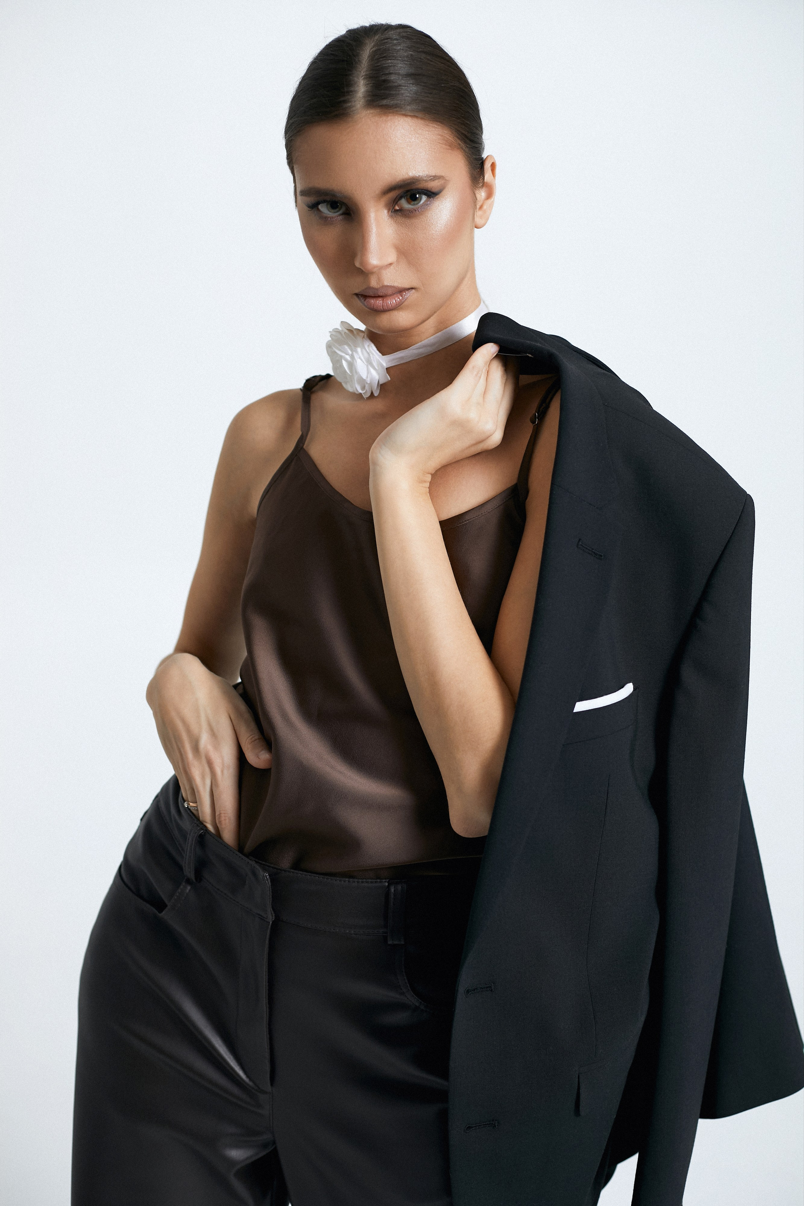 Красивая девушка в черном пиджаке, коричневом атласном топе на белом фоне