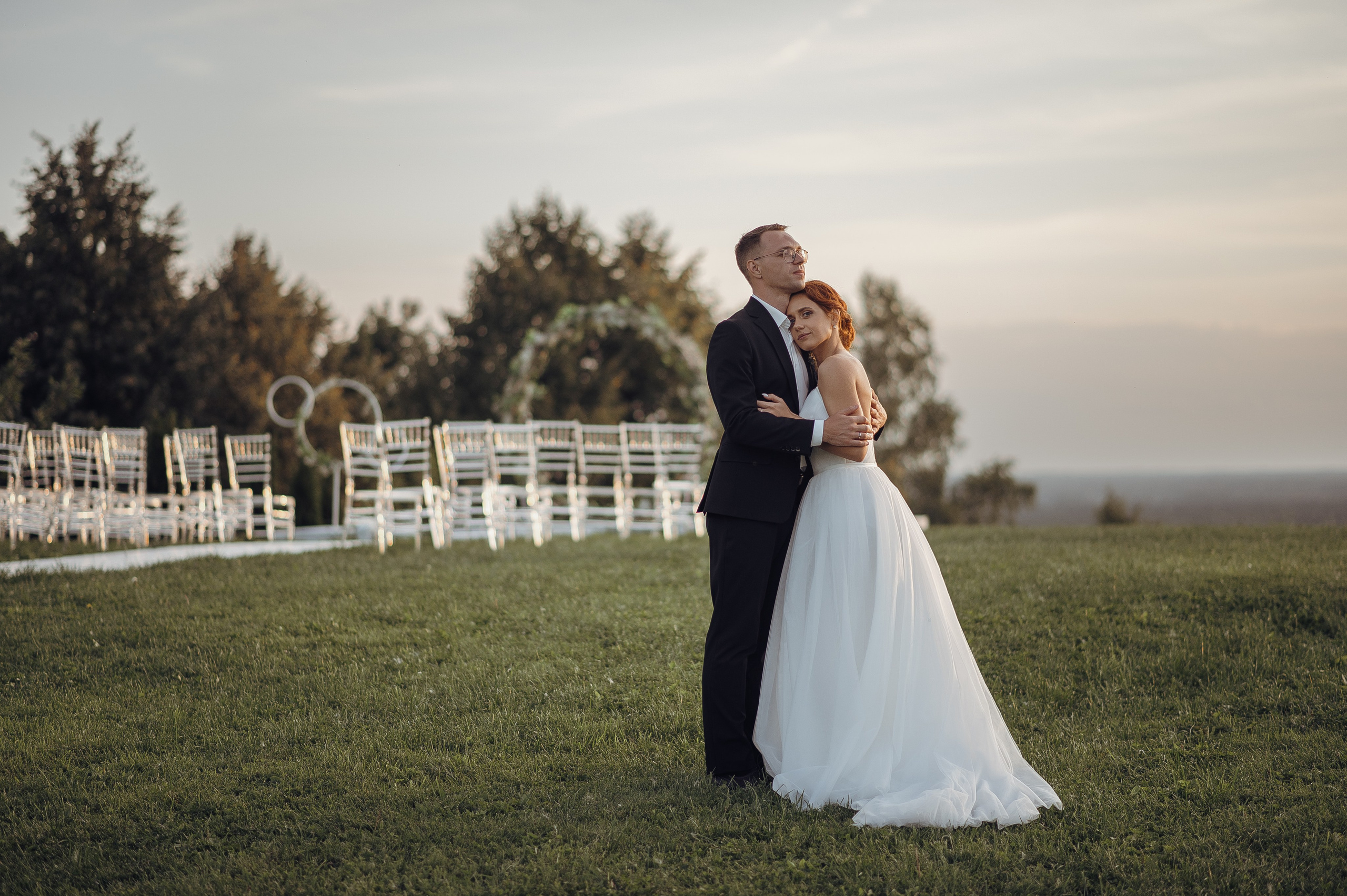 Влюблённое фото молодожёнов на закате на фоне свадебной арки