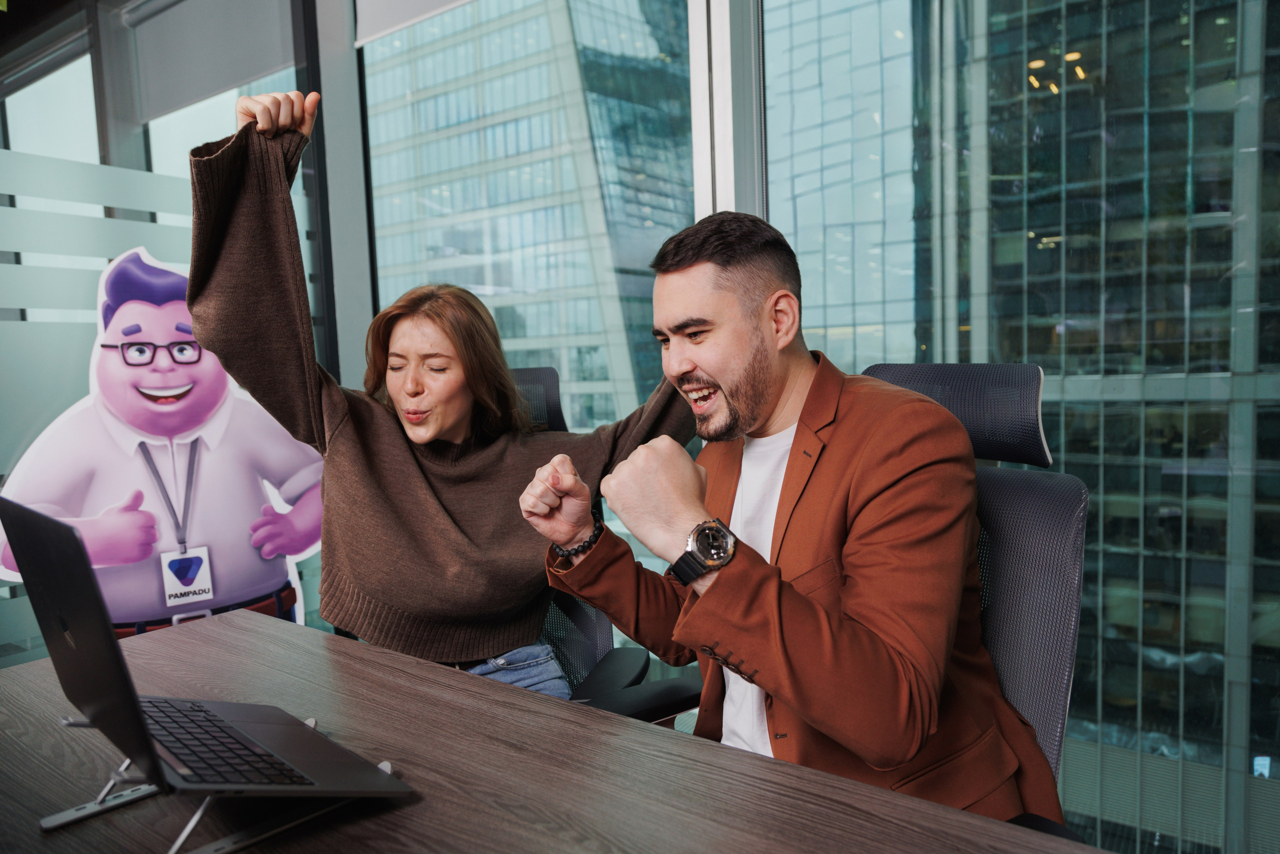 Два сотрудника IT-компании празднуют успешное завершение этапа проекта. Естественная репортажная съемка.