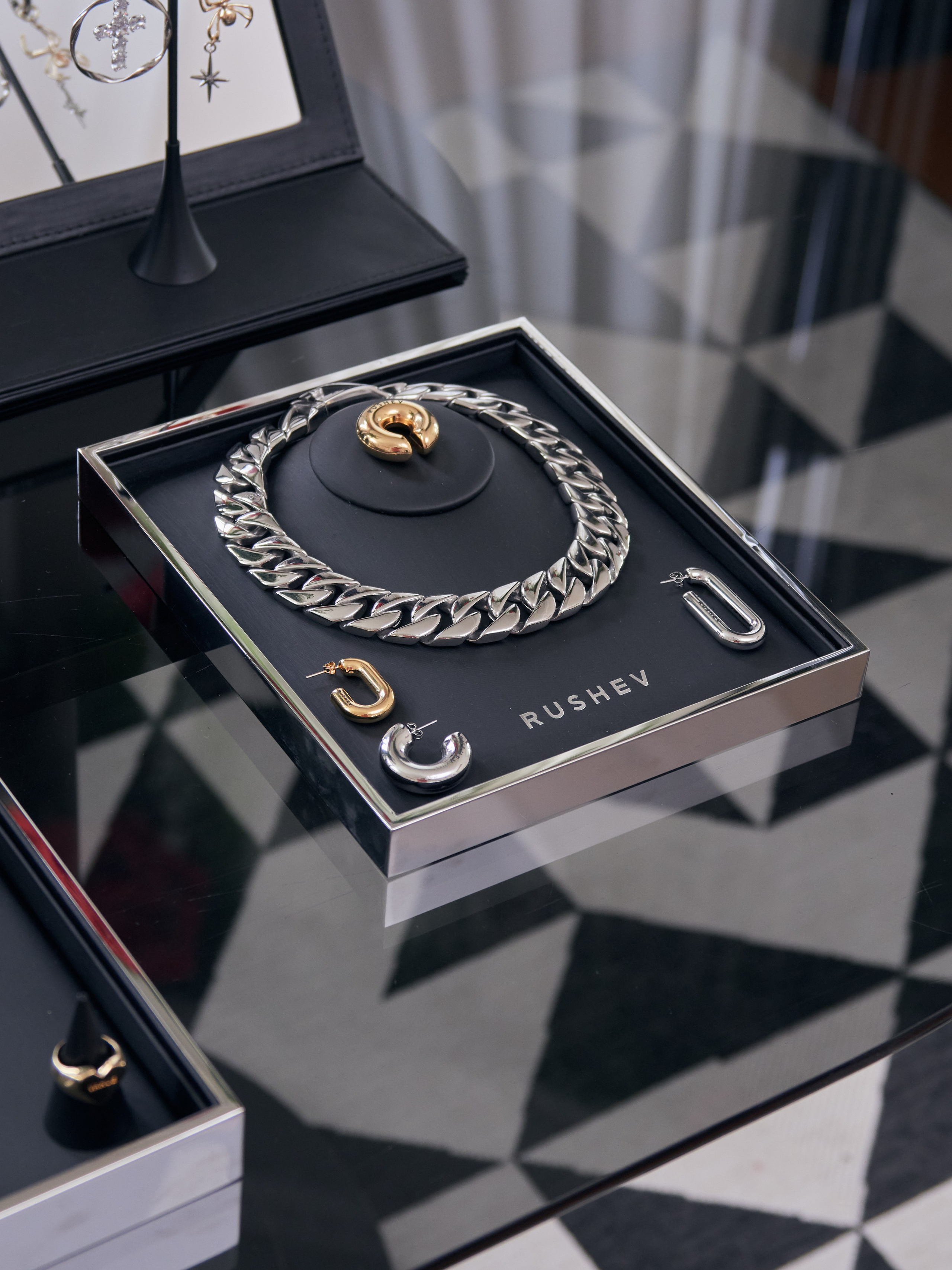 Роскошная витрина с колье и серьгами на стеклянном столе и логотипом RUSHEV