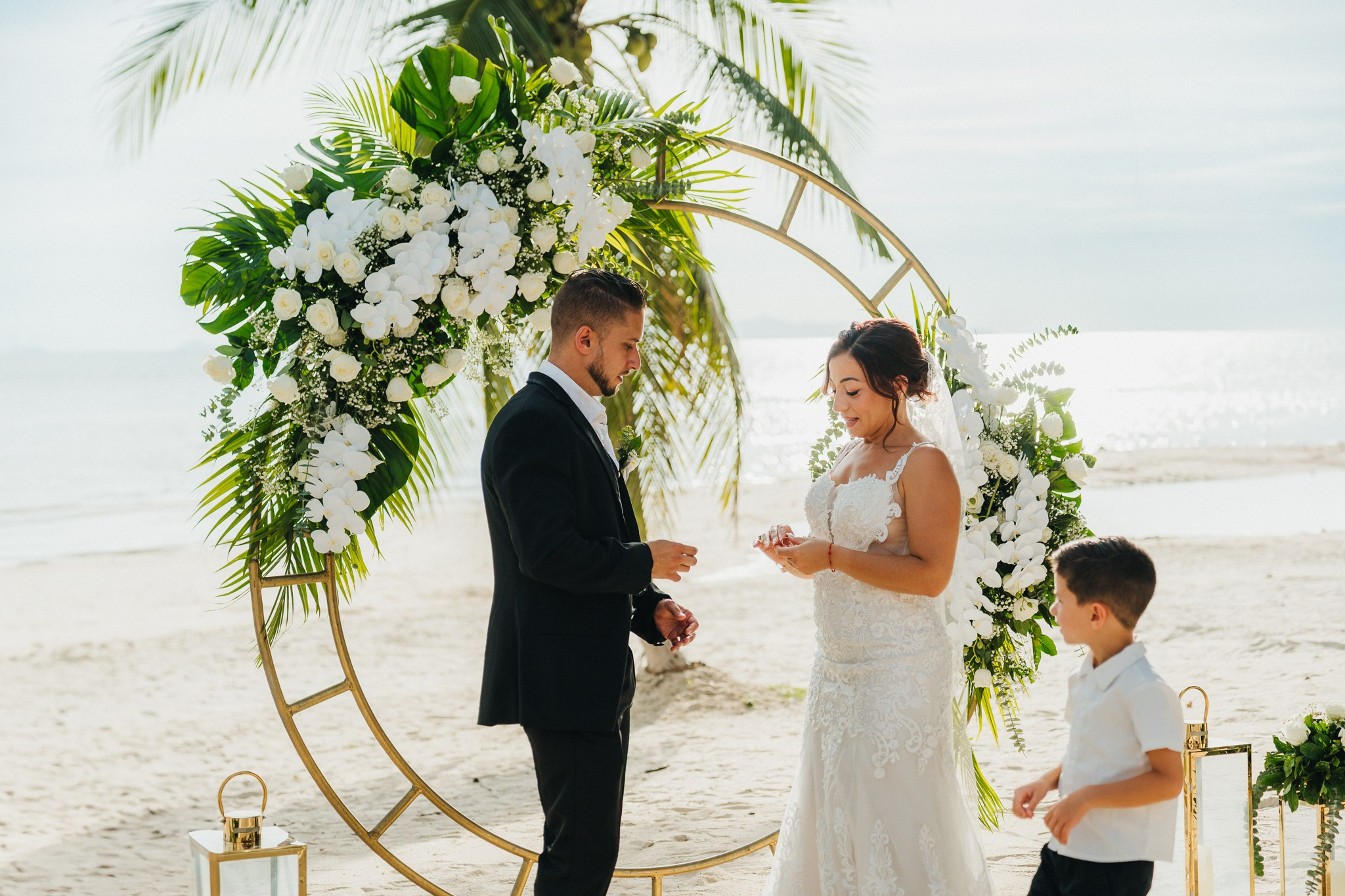 Bride and groom celebrating a beach wedding with their children in Koh Samui, Thailand, surrounded by tropical scenery and ocean views