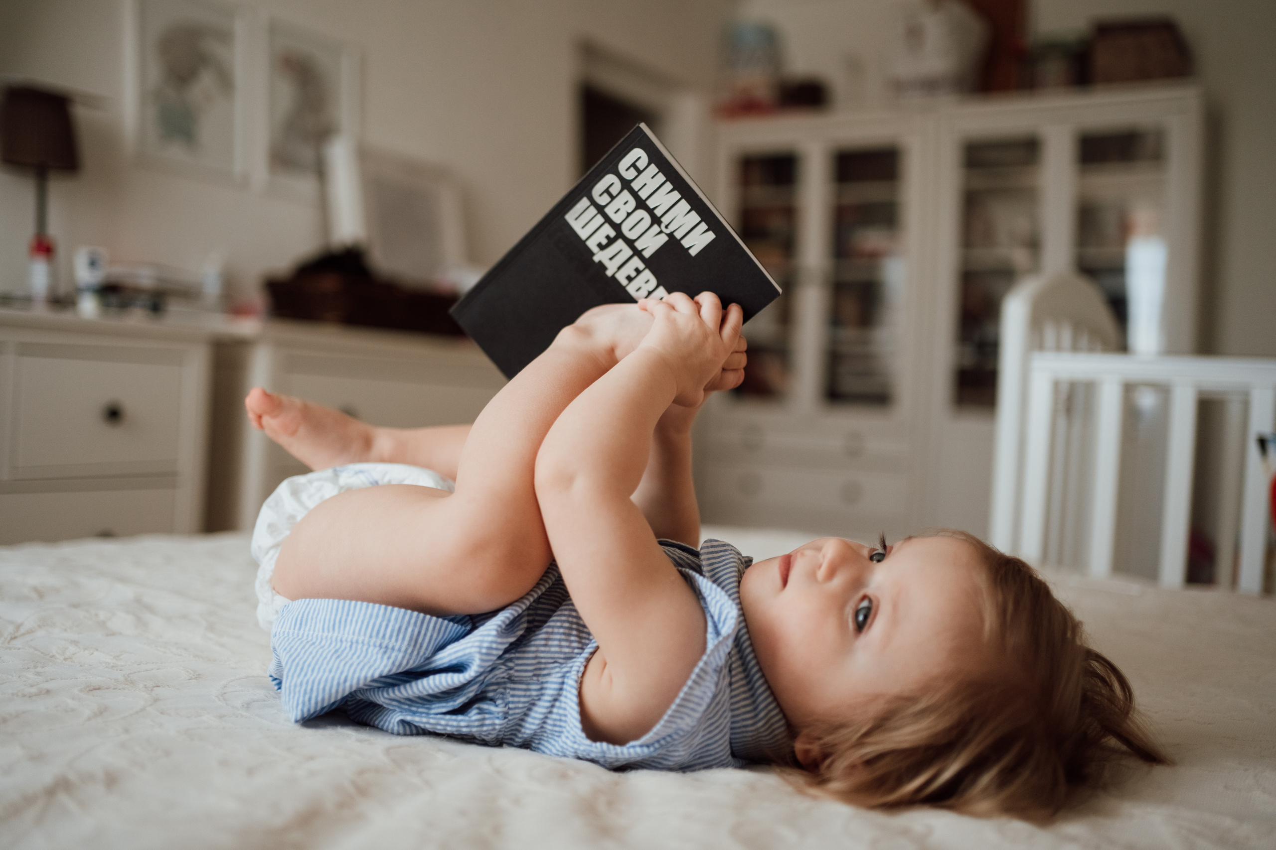 Ребенок лежит на кровати с книгой