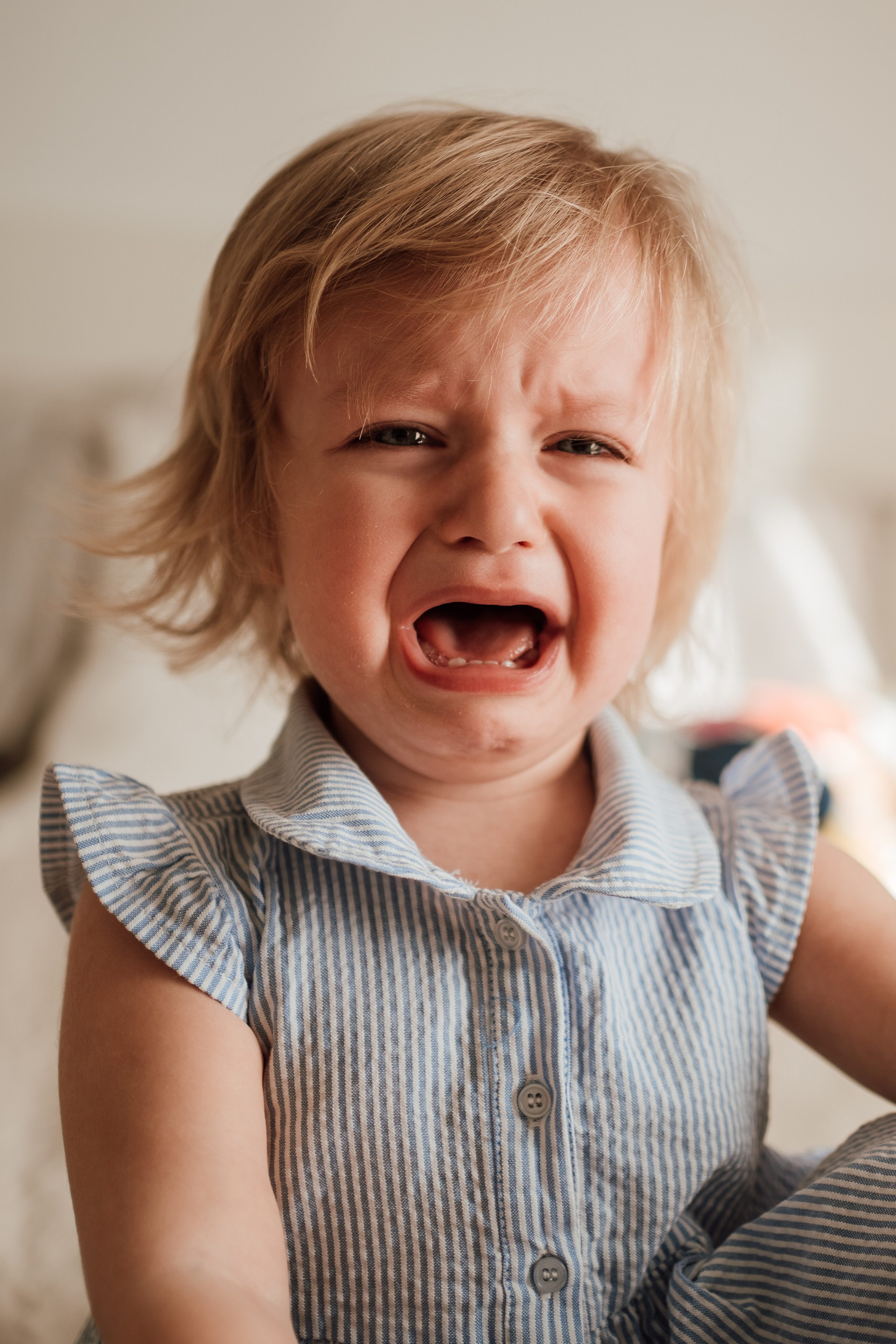 Маленькая девочка в голубом платье плачет