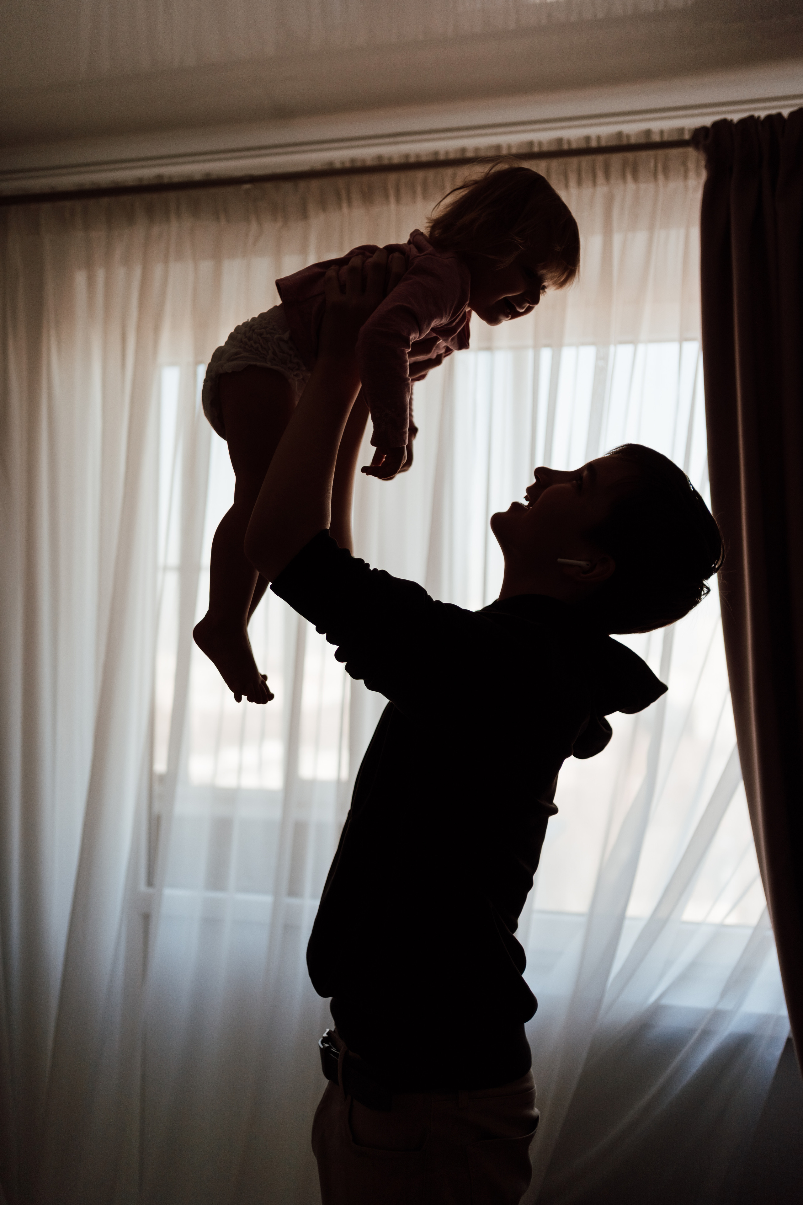 Молодой человек поднимает ребенка в контровом свете