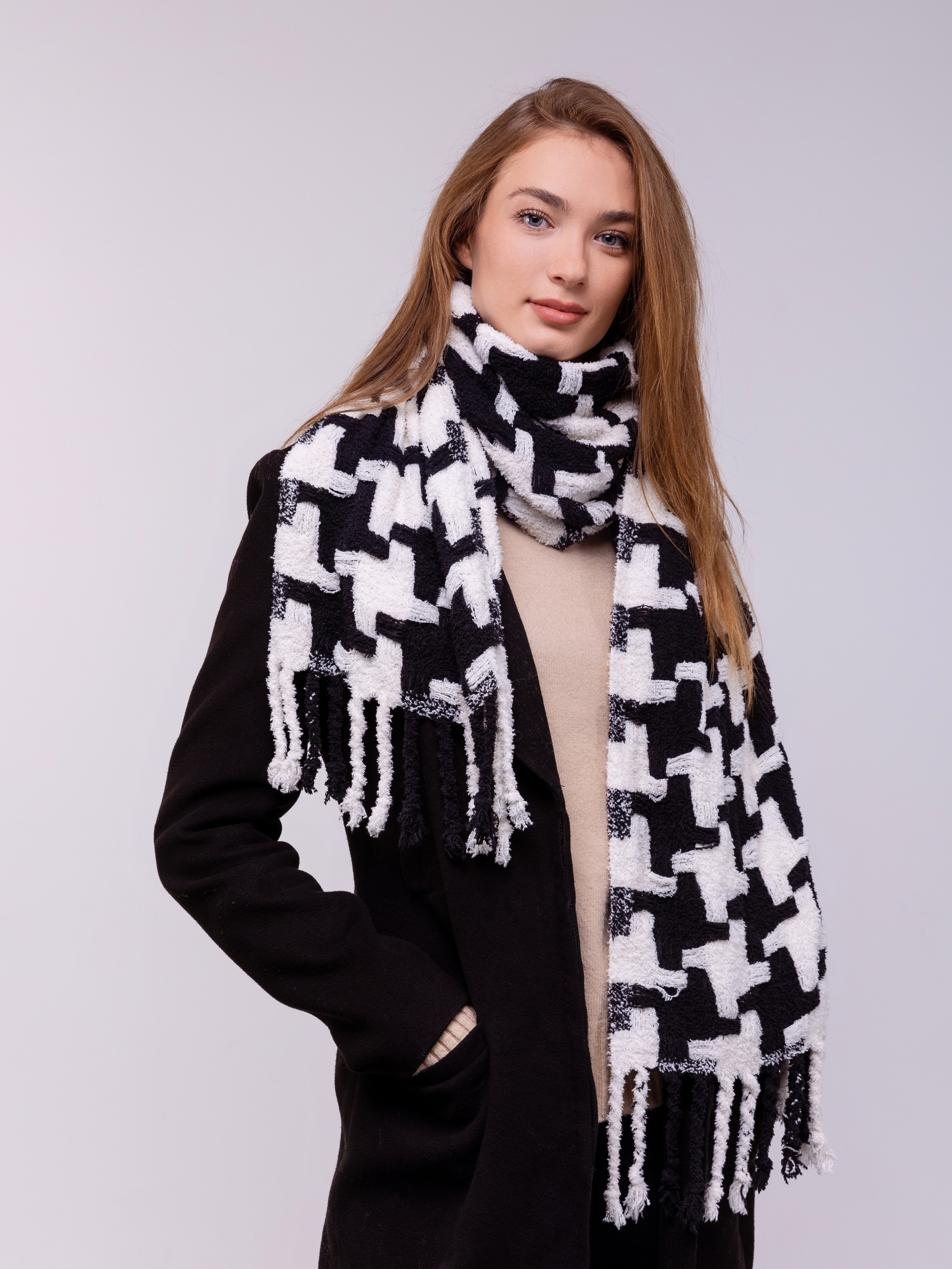 Девушка в черном пальто и шарфе с бахромой в бело черной гамме.
