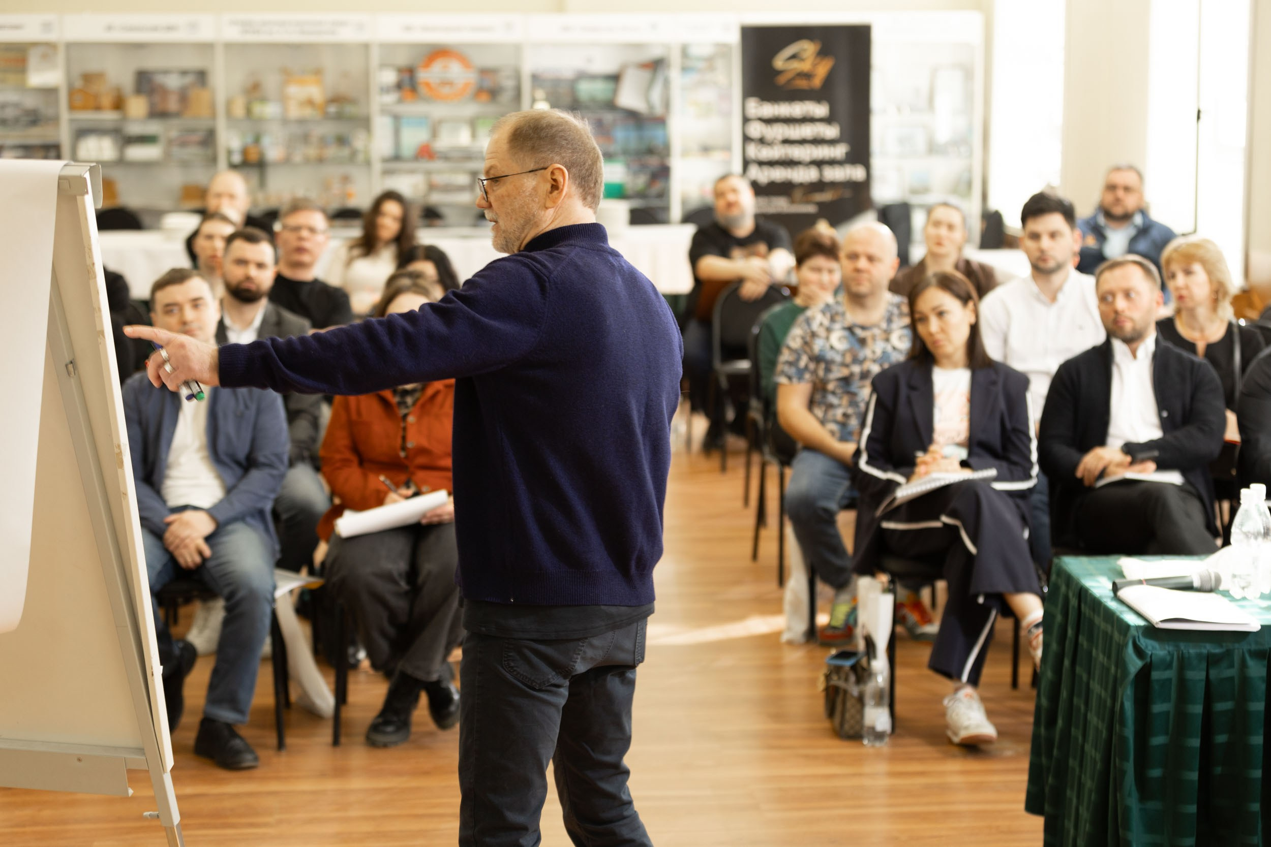 Спикер (вид со спины) использует флип чарт на бизнес семинаре.