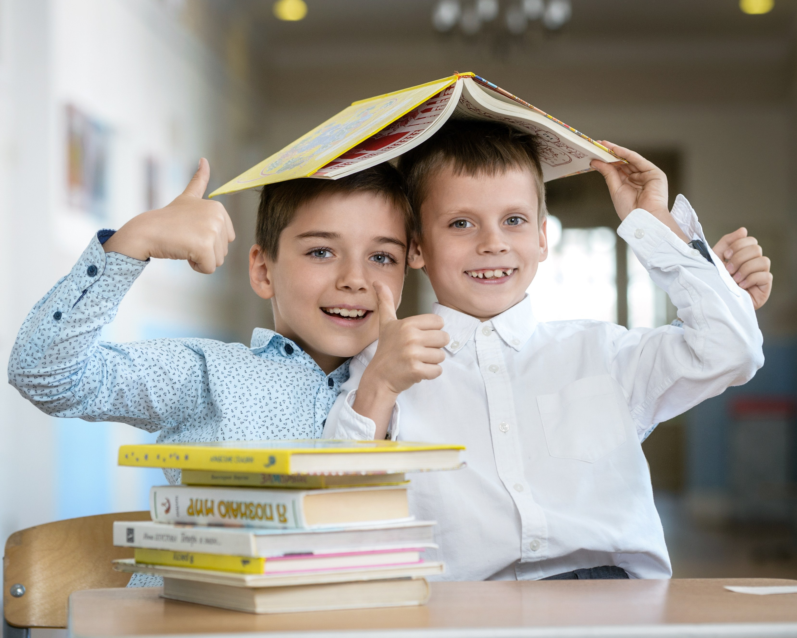 Два мальчика накрылись книгой за партой с учебниками