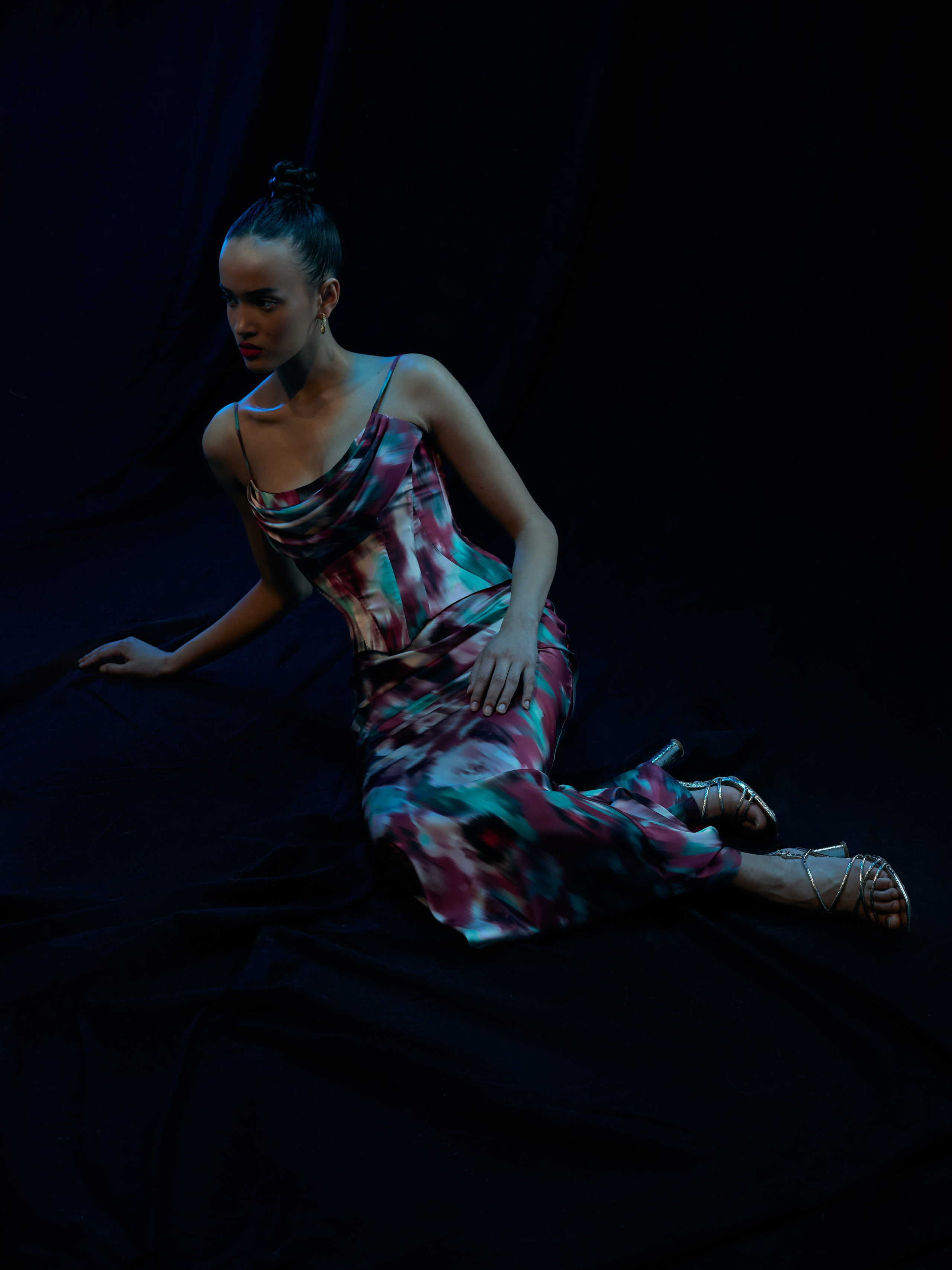 Съёмка лукбука - девушка лежит на черном фоне в шелковом платье с крупным цветным рисунком 