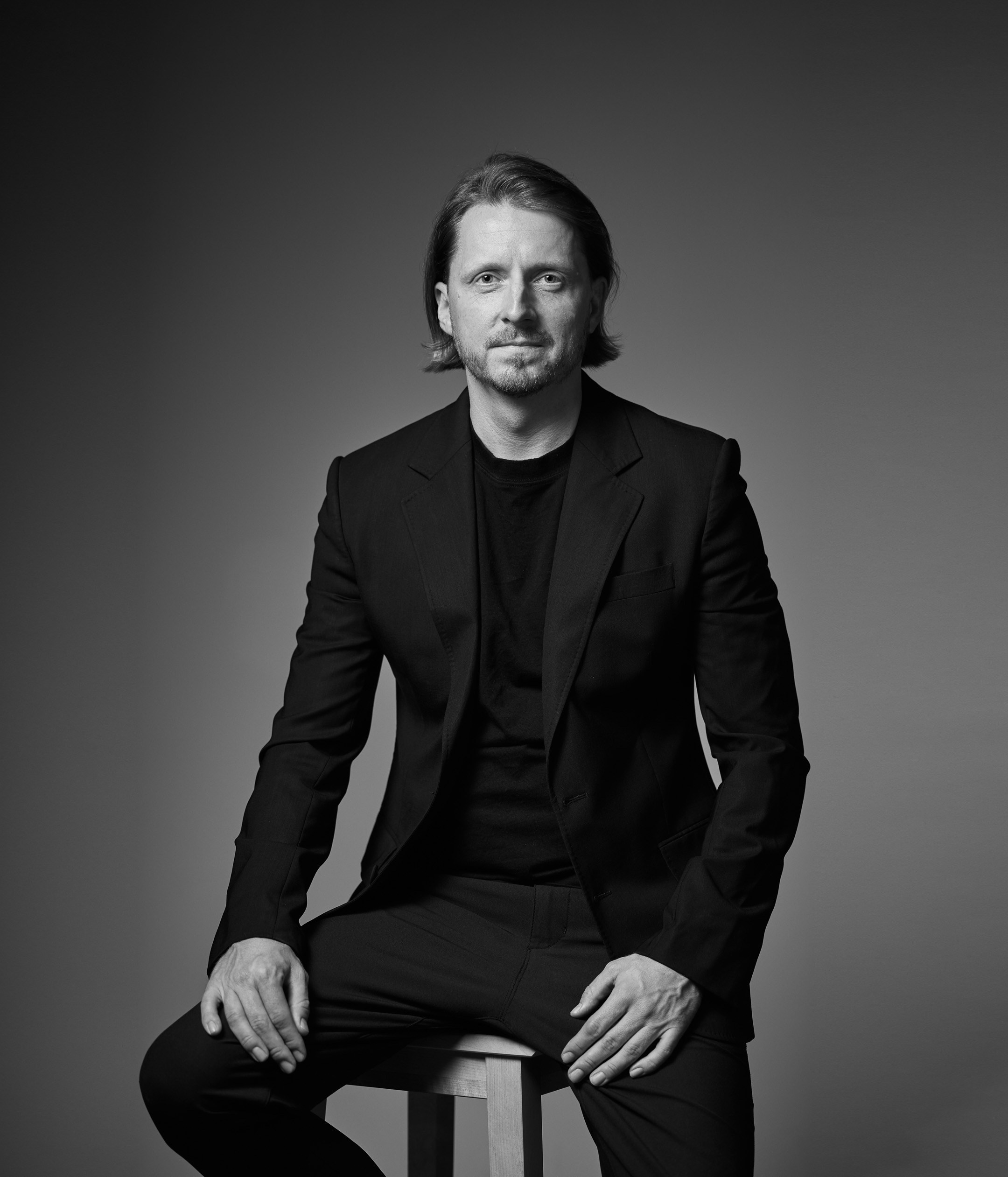 Black and white business portrait of a confident man in a suit on a dark studio background