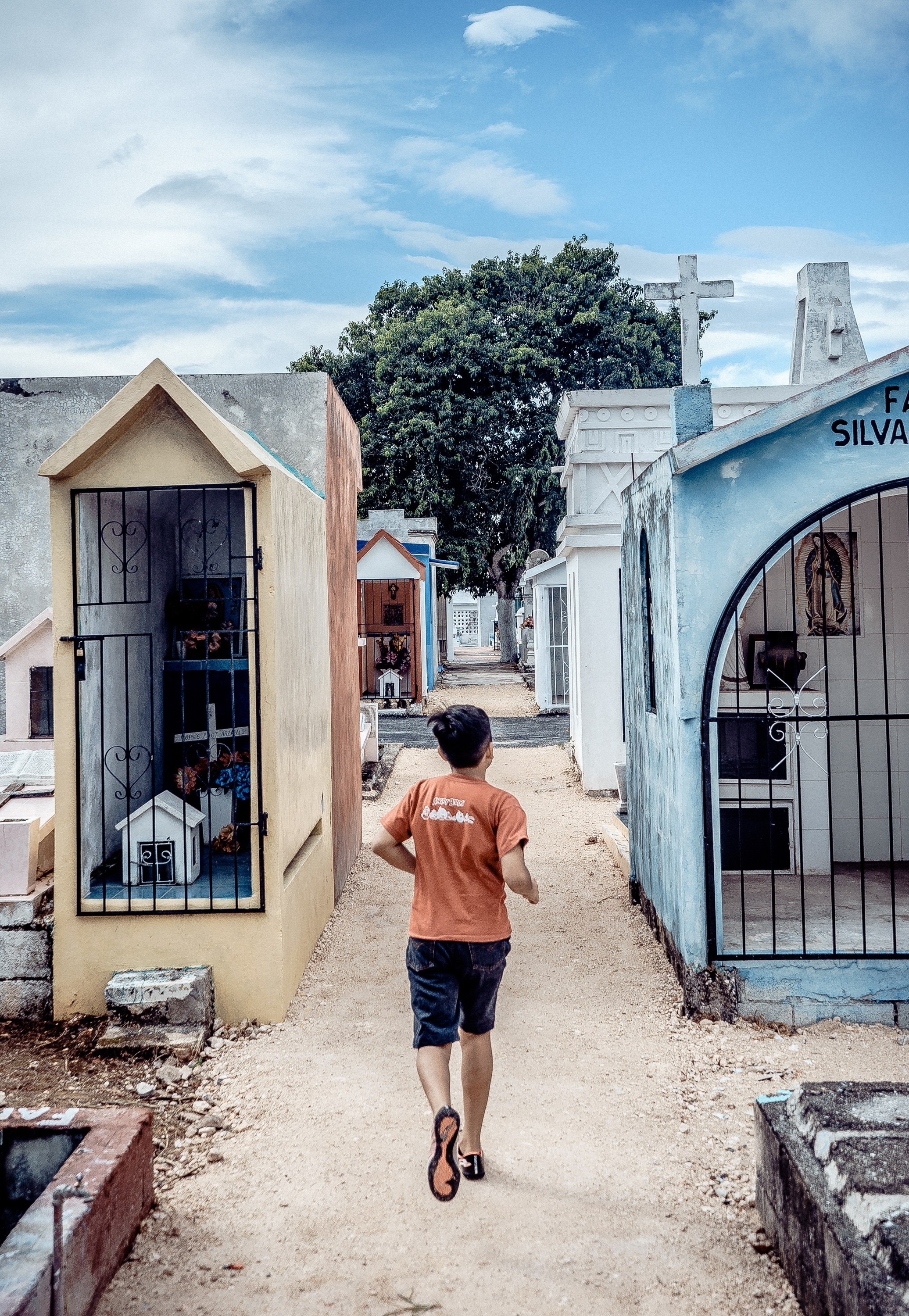 Мальчик бежит по кладбищу.